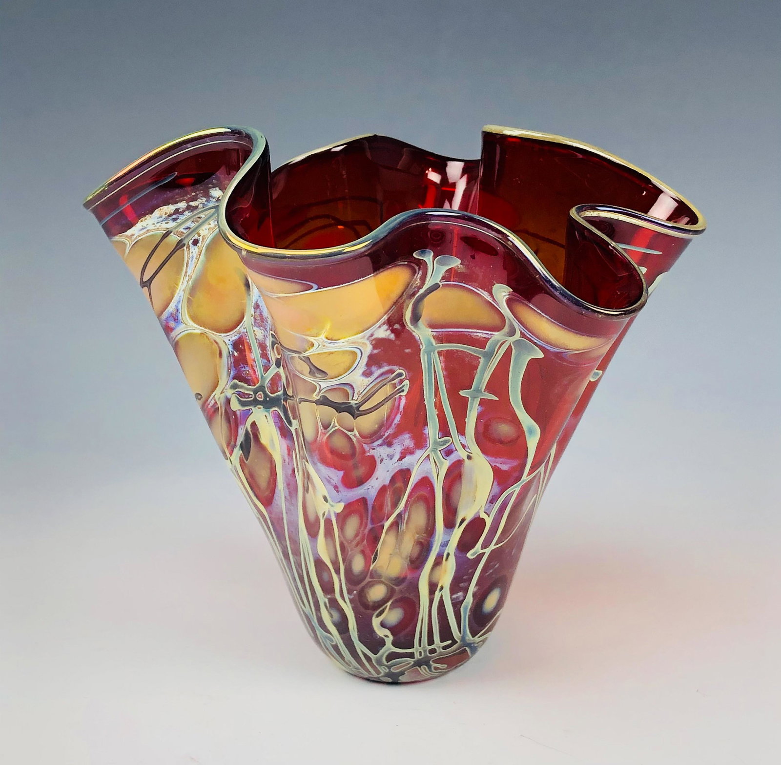 Mystery Artist Blown Art Glass Handkerchief Vase: Features a painstakingly studio hand blown art glass handkerchief vase. Graced with a distinctive yellow peach colored oil drop iridescent design with threaded like forms around, against a warm red gr