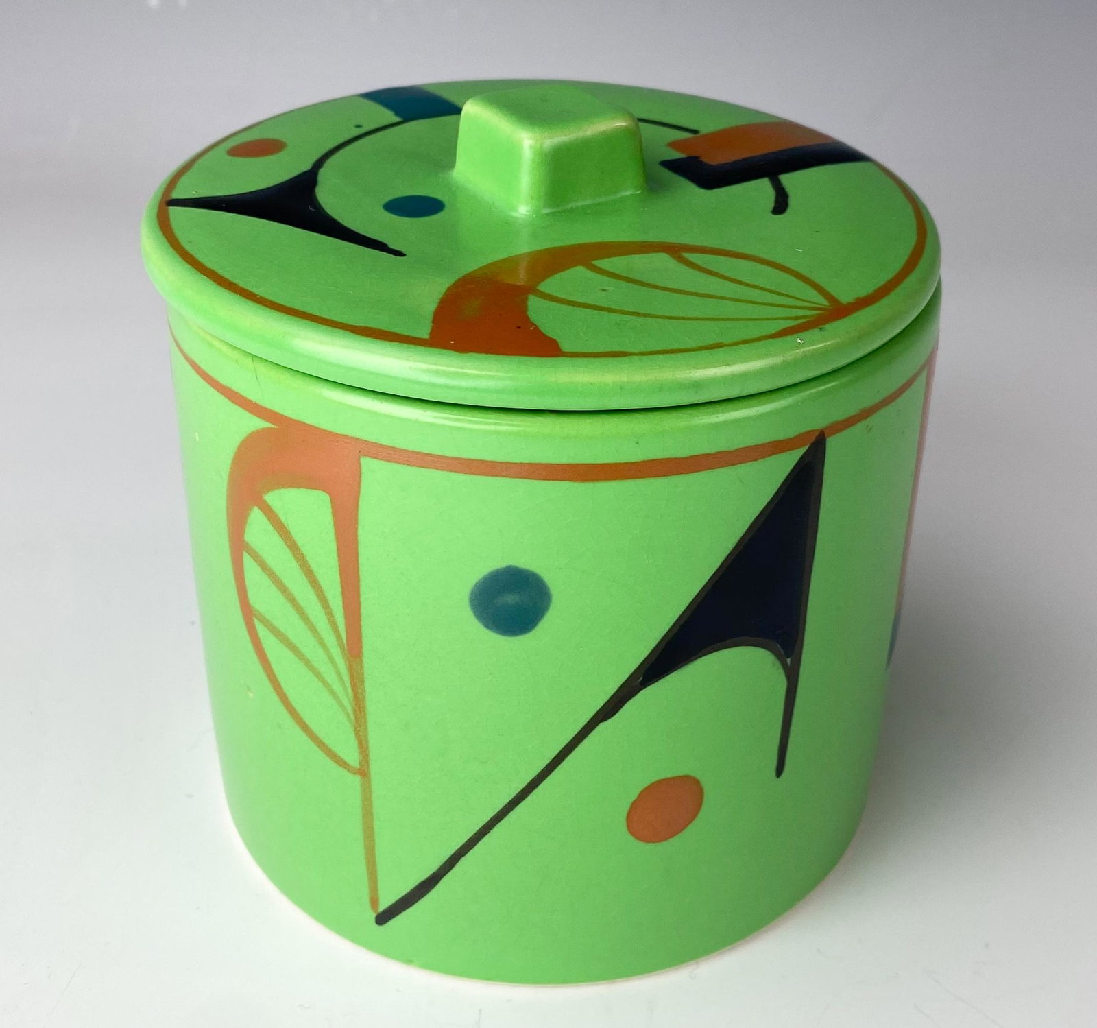 Mid Century Painted Ceramic Japanese Lidded Jar: Decorative as well as a functional ceramic article of Japanese origin. Graced with hand painted abstract designs against a green ground. Partial matte and partial gloss finish. Signed Made in Japan. G