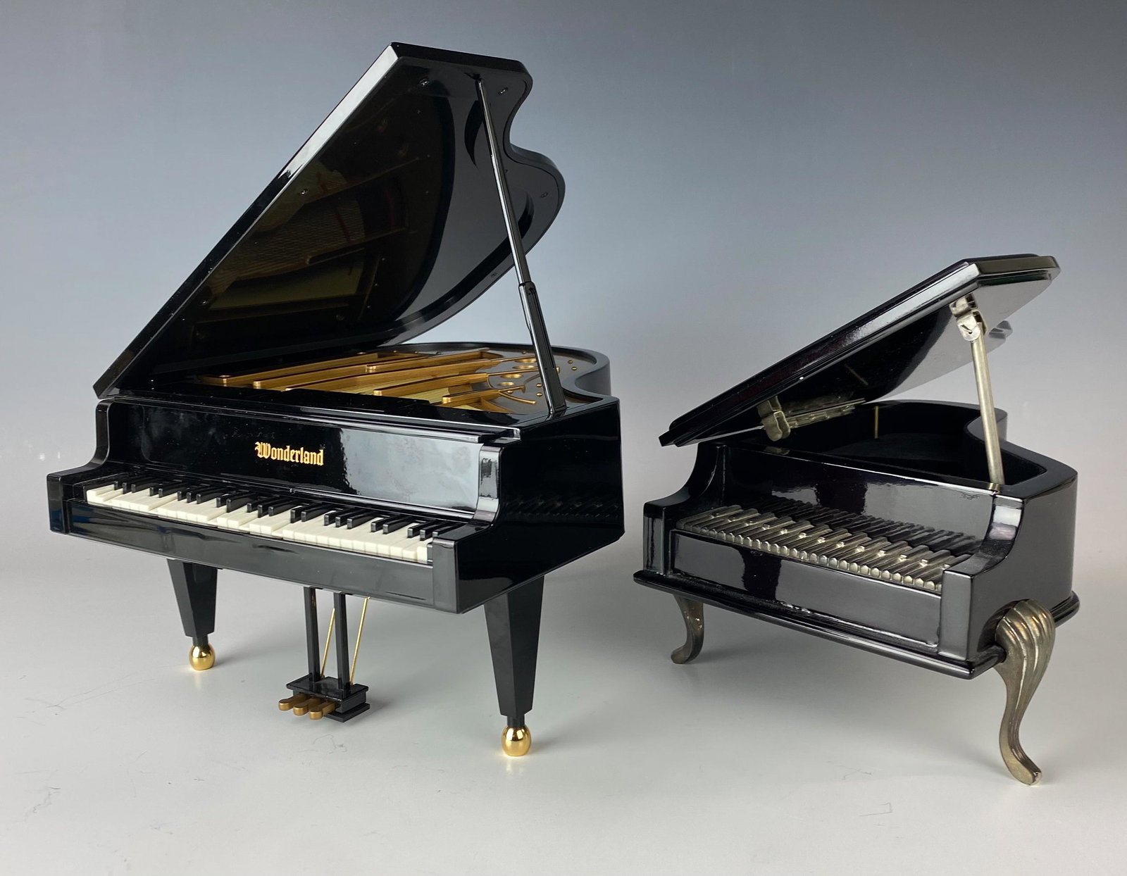 2 Mini Miniature Grand Piano Music Musical Boxes: Estate lot 2 Mini Grand Piano Musical Boxes. The larger black colored piano stamped Wonderland. The smaller dark brown colored piano is unmarked. Appear to be constructed of some plastic material. No 