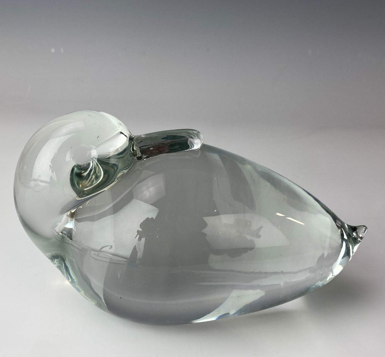 Mystery Maker Hand Blown Art Glass Duck Sculpture: Solid, thick walled and a heavy clear glass sculpture of a seated duck bird. Crystal clear clarity. Smooth high mirror polished base. Unsigned. Estate fresh condition. Surface wear and scratch lines o