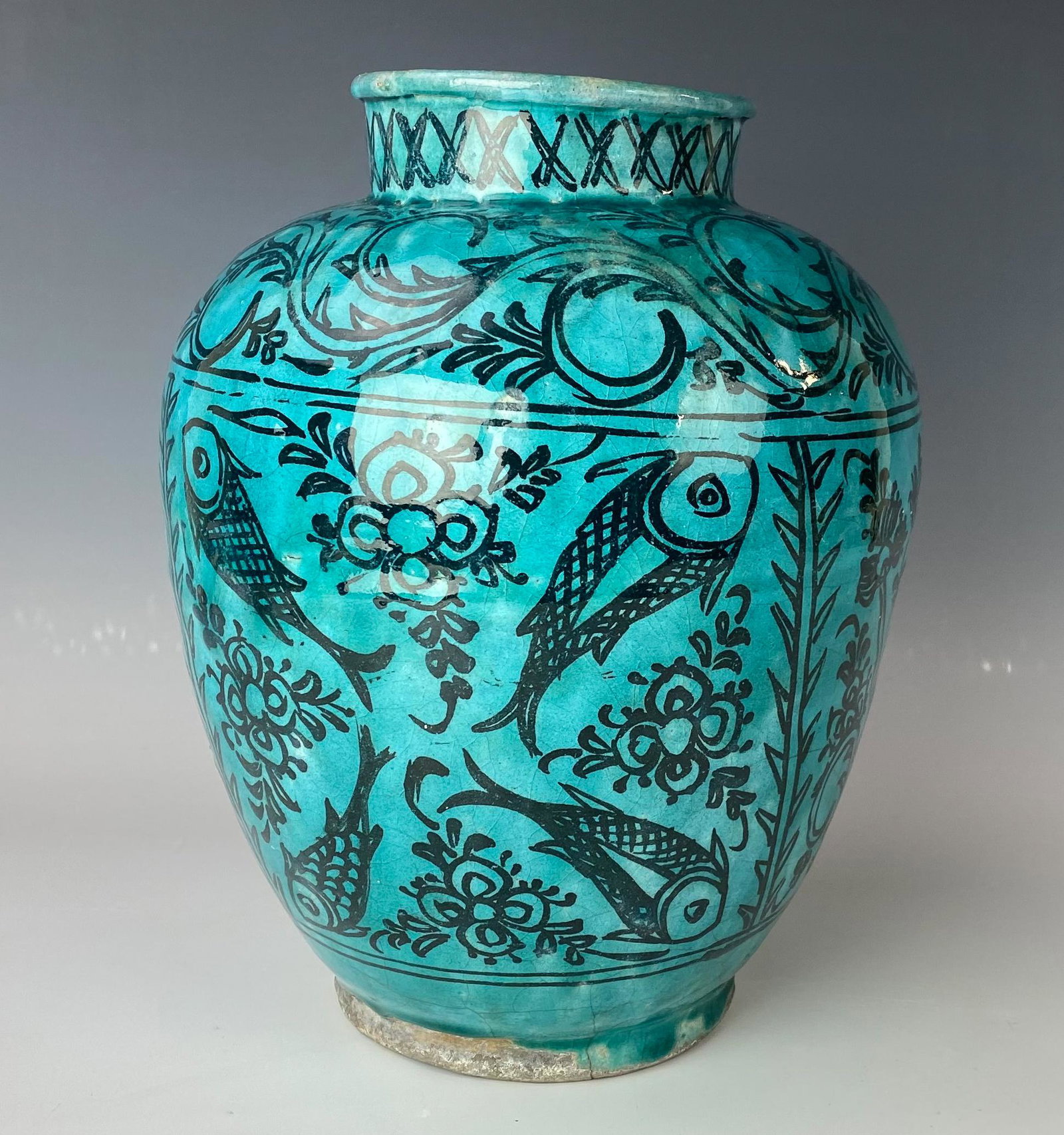 Mystery Maker 11" Painted Ceramic Fish Floral Vase: Painstakingly hand crafted ceramic pottery vase graced with a fish, floral and a scroll motif in black, against a green colored ground. Warmly glazed in manner. Unsigned. Minor chips, around, includin
