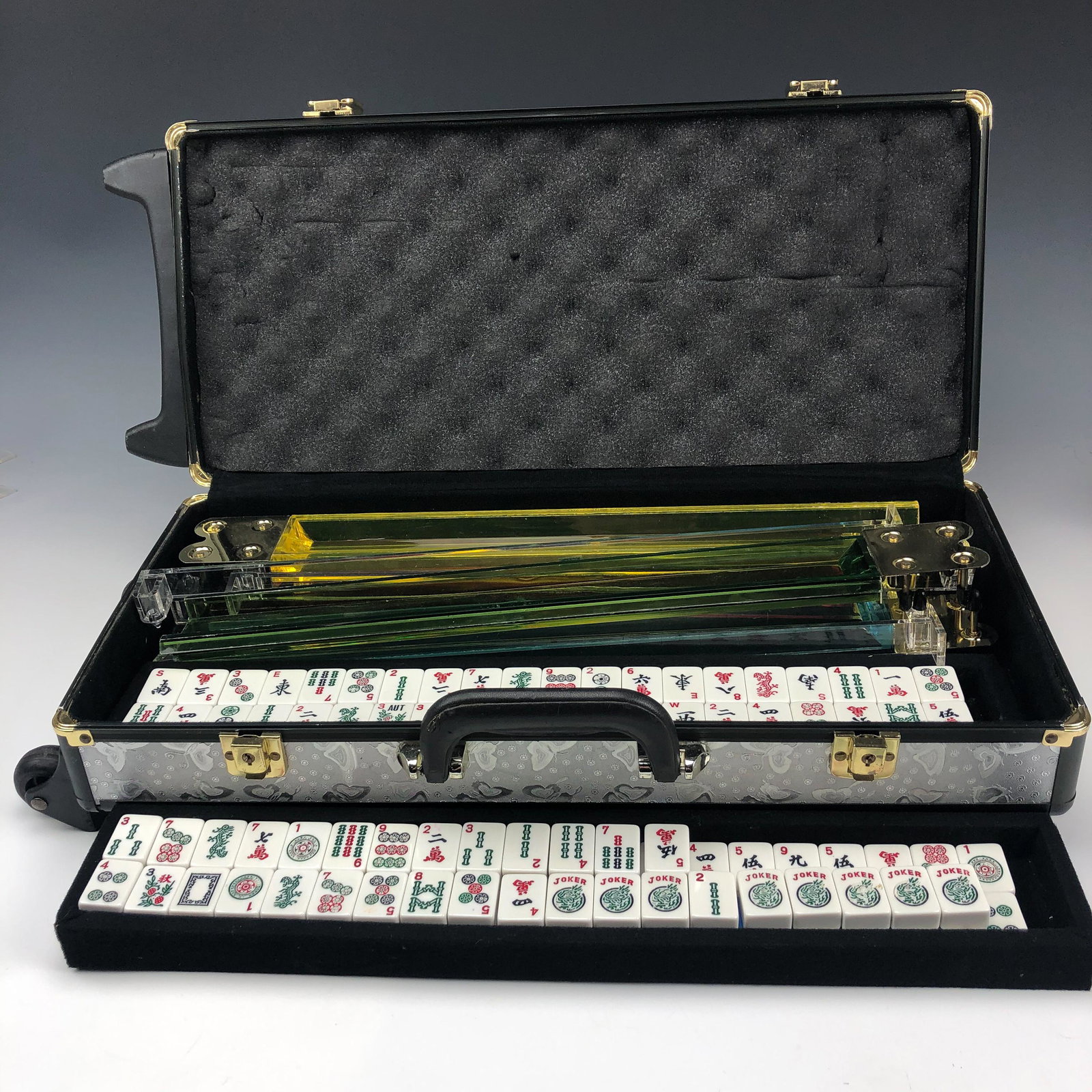 Mahjong Board Game Set w/ 152 Tiles in Travel Case: Features a total of 152 white plastic Mahjong board game tiles and 4 colored plastic racks in a travel suitcase case on wheels. Of the 152 tiles, there are 8 jokers. Set is preowned. Unsigned. Good es