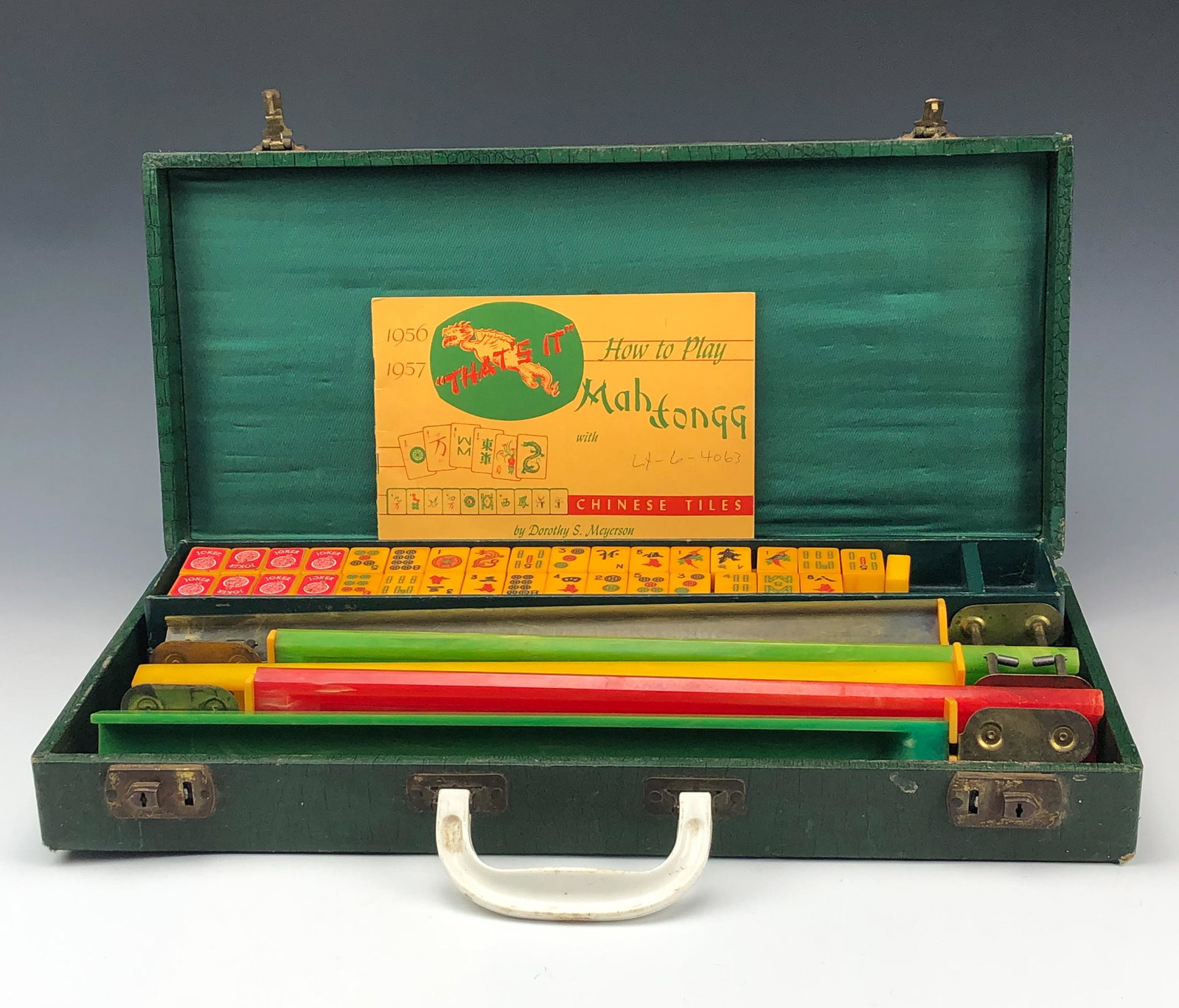 Mahjong Board Game w/ 152 Bakelite Tiles & 5 Racks: Included are a total of 152 yellow bakelite tiles, of which 8 have red joker stickers on them. There are 5 different colored racks. Nicely housed in a green colored carry box. Comes with an instructio