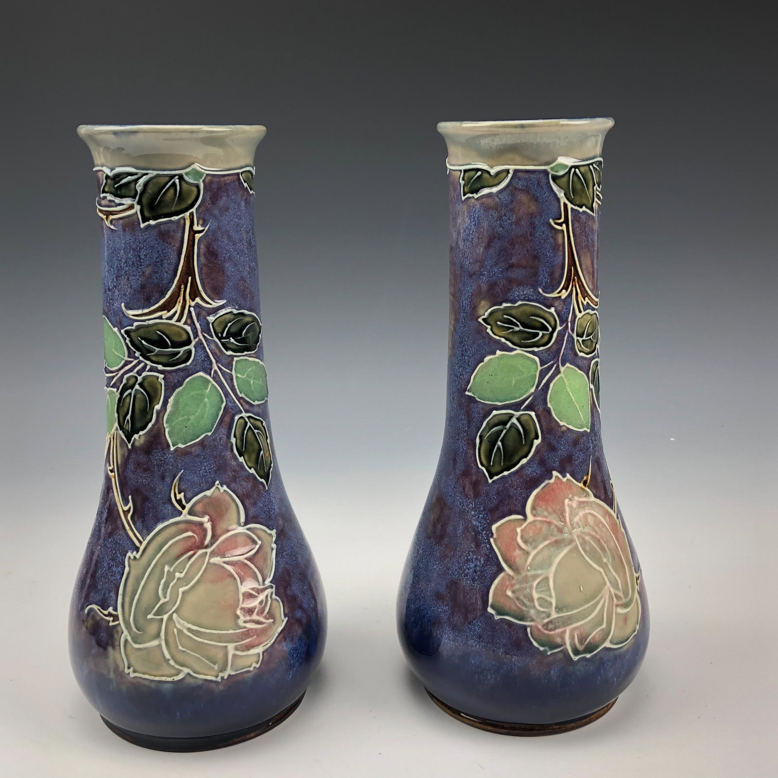 Pr Royal Doulton Lambeth Art Nouveau Floral Vases: Stunning pair of English origin hand crafted ceramic stoneware pottery vases. Modeled with a strongly influenced Art Nouveau design. The tube lined decoration features a large bloomed rose with thorny