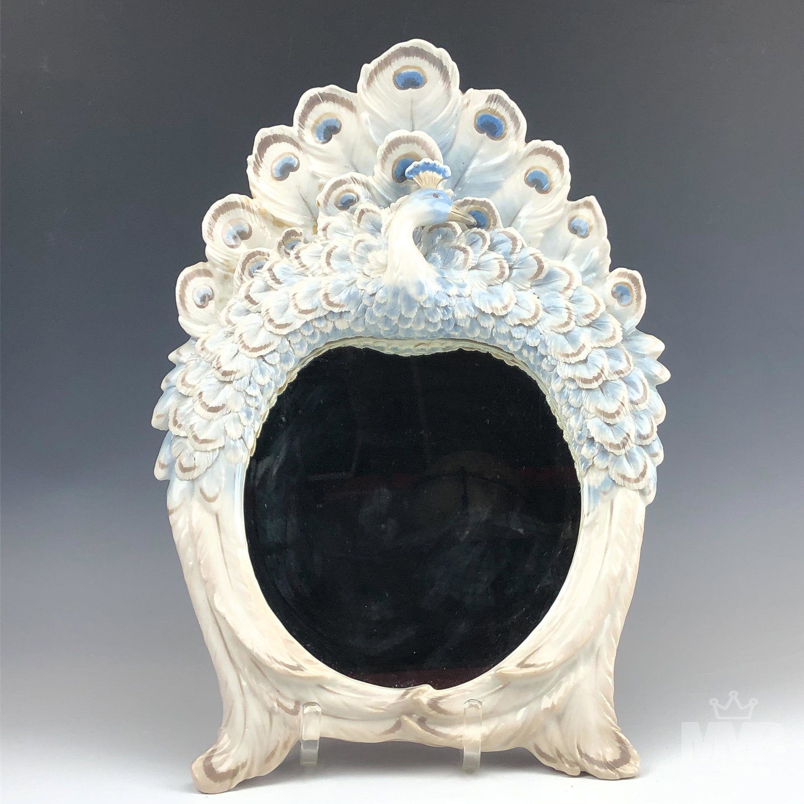 Peacock Bird Porcelain Blue & White Wall Mirror: Wall mirror crafted out of quality porcelain. Features a blue and white peacock feathered bird. Fair condition with repairs on top left. Measures approximately 14 in x 12 in. MMB in house USA continen