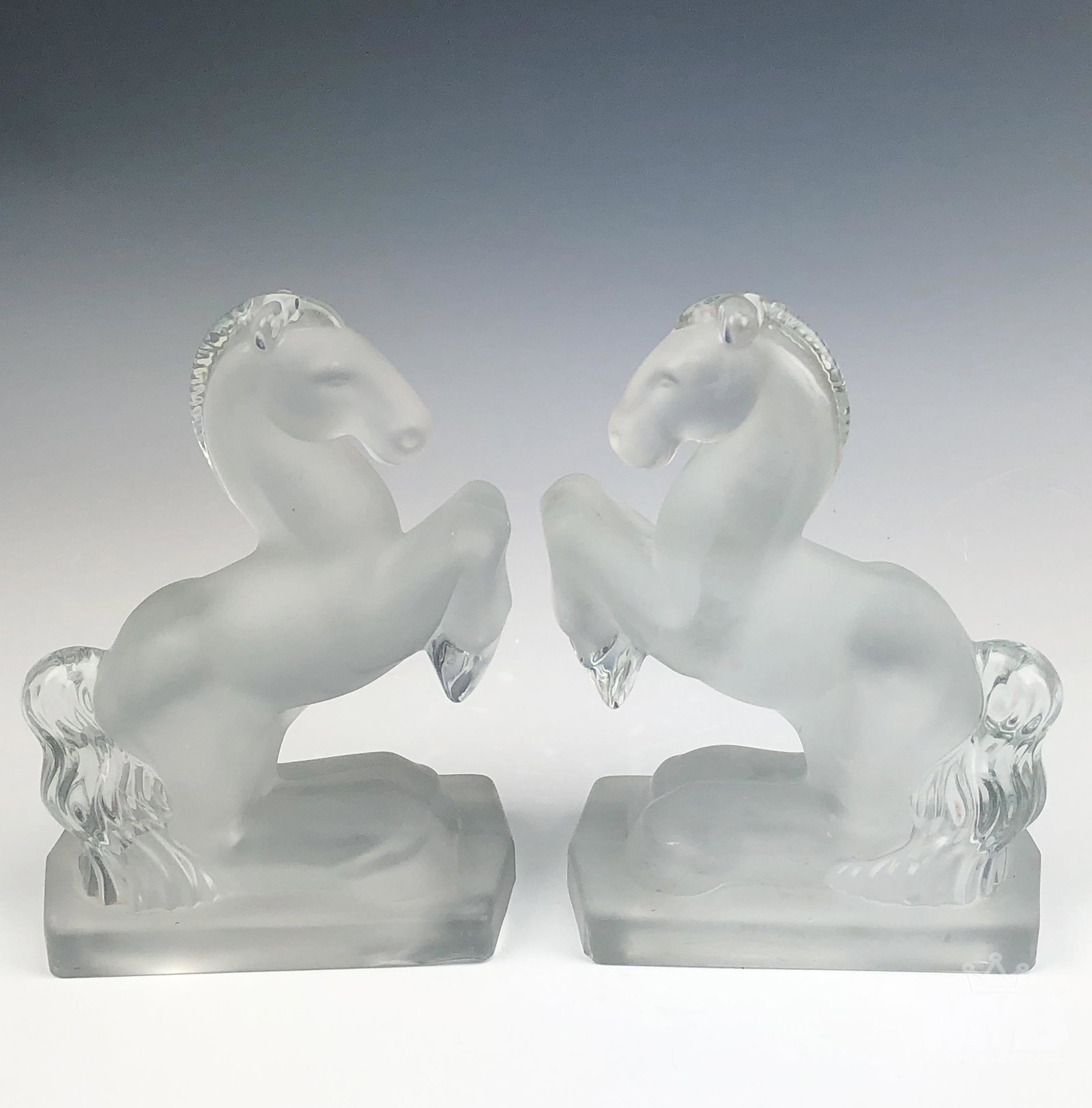 Pair of Frosted Art Glass Rearing Horse Bookends: Pair of horse bookends. Made from frosted glass featuring a rearing horse. Hollow instead. Good overall condition with mild storage wear. Unsigned. Measures approximately 7 1/2 in. x 6 in. x 3 in. MMB