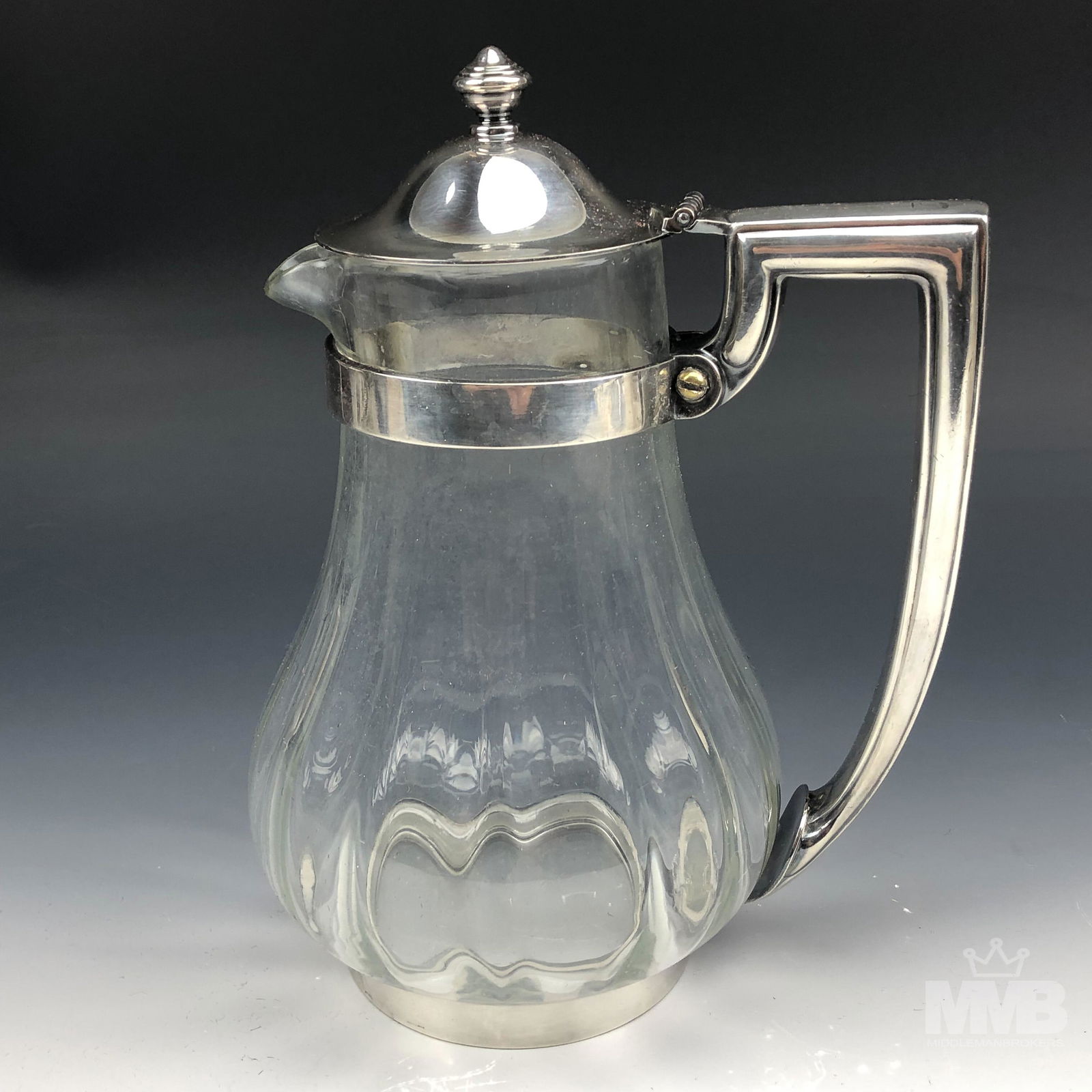 Reed & Barton Silver Soldered Ribbed Glass Pitcher: Solid sturdy and a well crafted glass claret pitcher jug with pouring spout. Silver soldered mounted hardware with angular shaped handle with circular base. Vertical ribbed patterns grace the bulbous