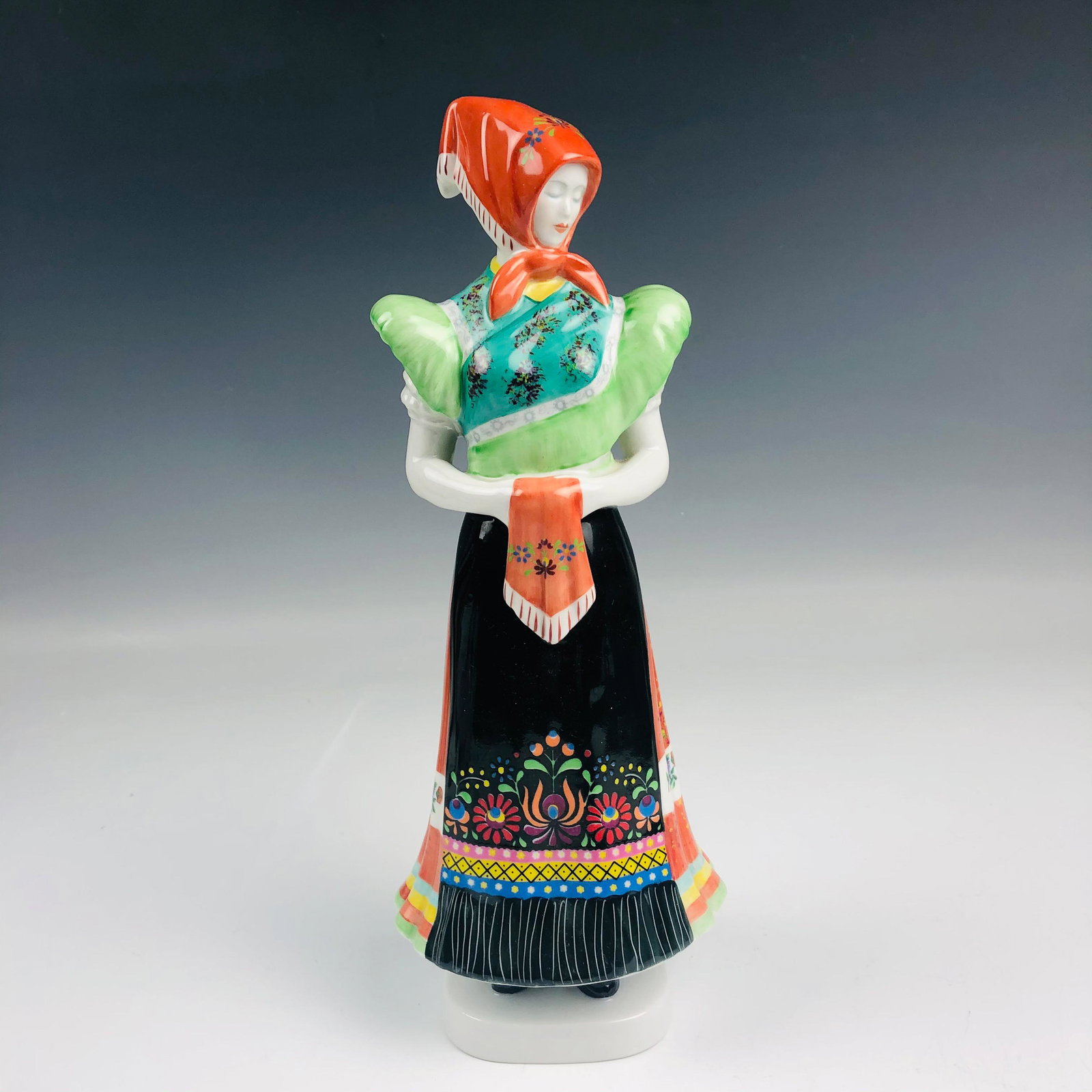 Hollohaza Porcelain Folk Art Peasant Girl Figurine: Hollohaza Hungary Hand Painted Hungarian Porcelain Folk Art Peasant Girl Figurine. Depicts a young maiden in traditional ethnic garb with hands joined in the front, in standing pose. Pretty colors. Wa
