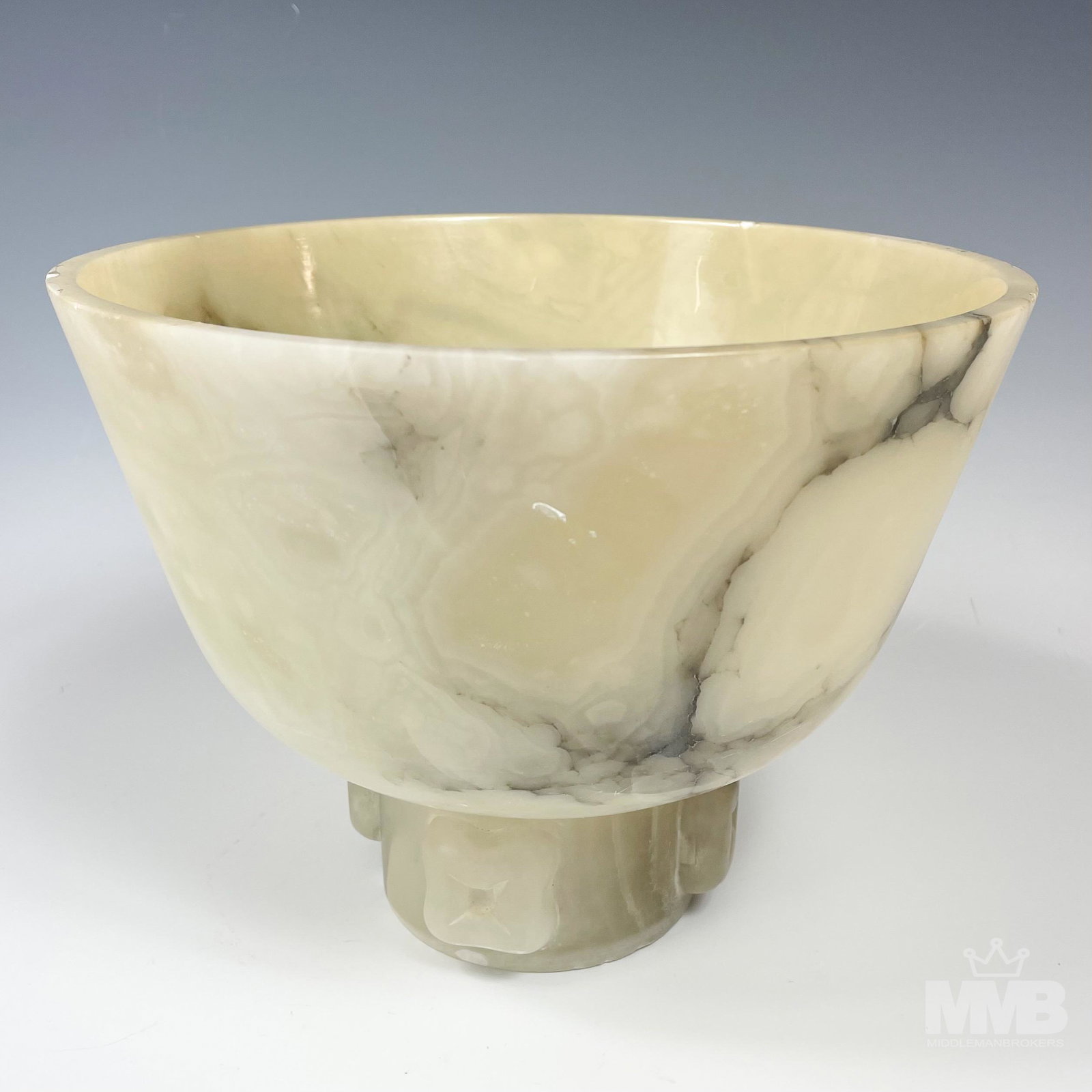 Polished Alabaster Hardstone Pedestal Centerbowl: Painstakingly hand carved in manner with a smooth high mirror polished finish. Of simple form with wide open mouth over short tubular base with 4 carved flower forms around. Warm natural matrix design