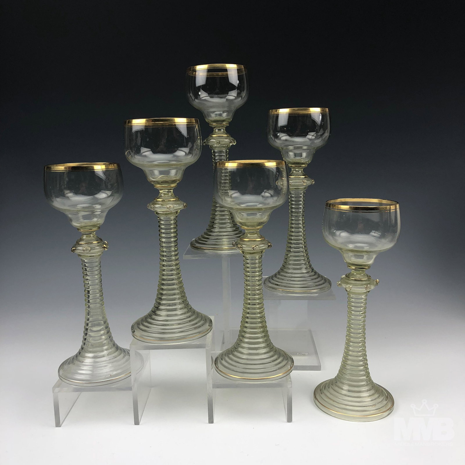 6 Roemer German Green Ribbed Stem Wine Glasses: Collection of six Roemer style wine glasses. Features a green coiled stem and a clear top with a gold gilt rim. Good overall condition with mild storage wear. Measures approximately 8 in x 3 in x 3 in