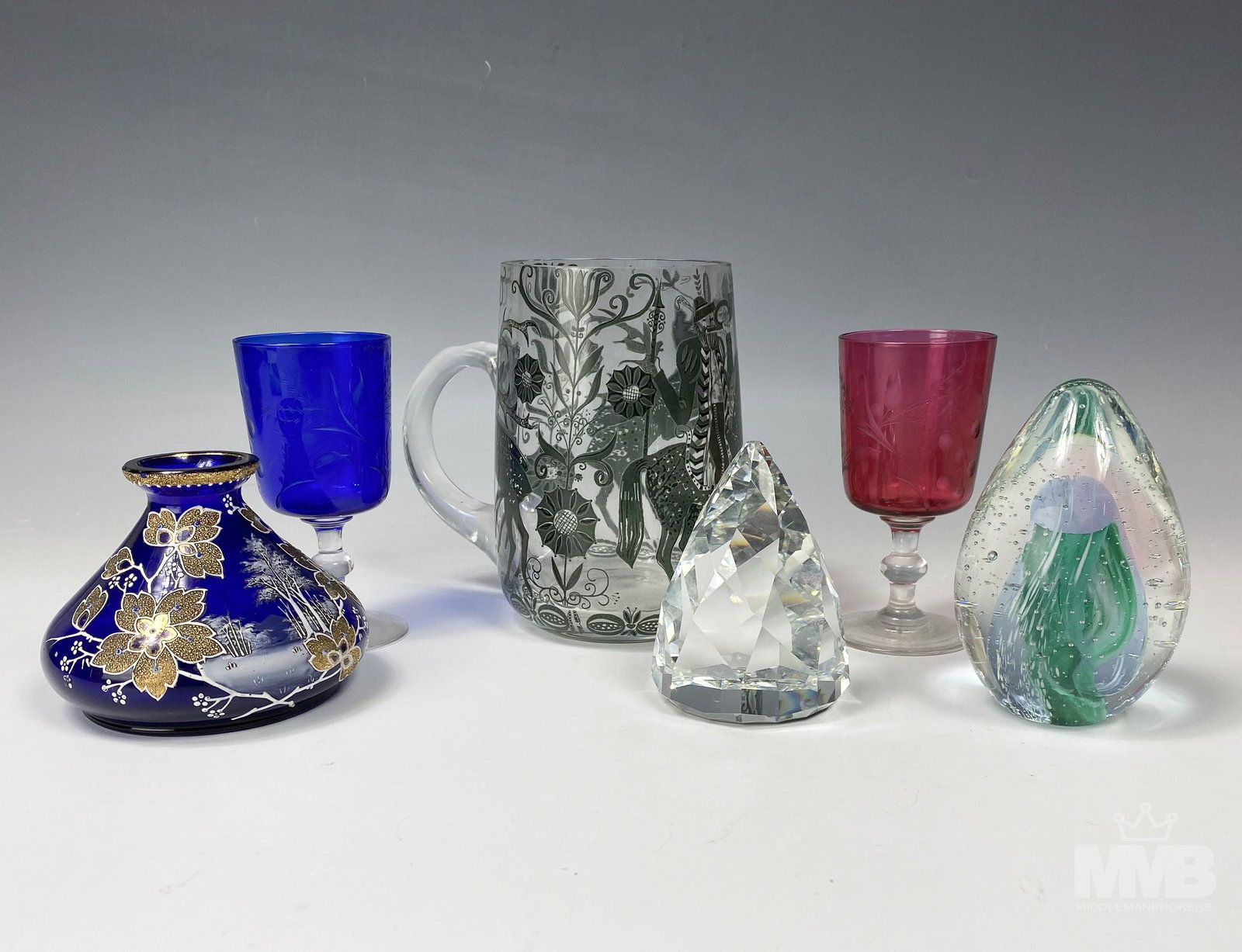 Lot 6 Assorted Art Glass Cups Paperweights & Vase: Collection of six assorted art glass pieces. Lot includes: (1) egg clear and green bubble paperweight measuring 4 in x 2 1/4 in x 2 1/4 in; (1) marked Swarovski pyramid paperweight measuring 3 1/2 in 