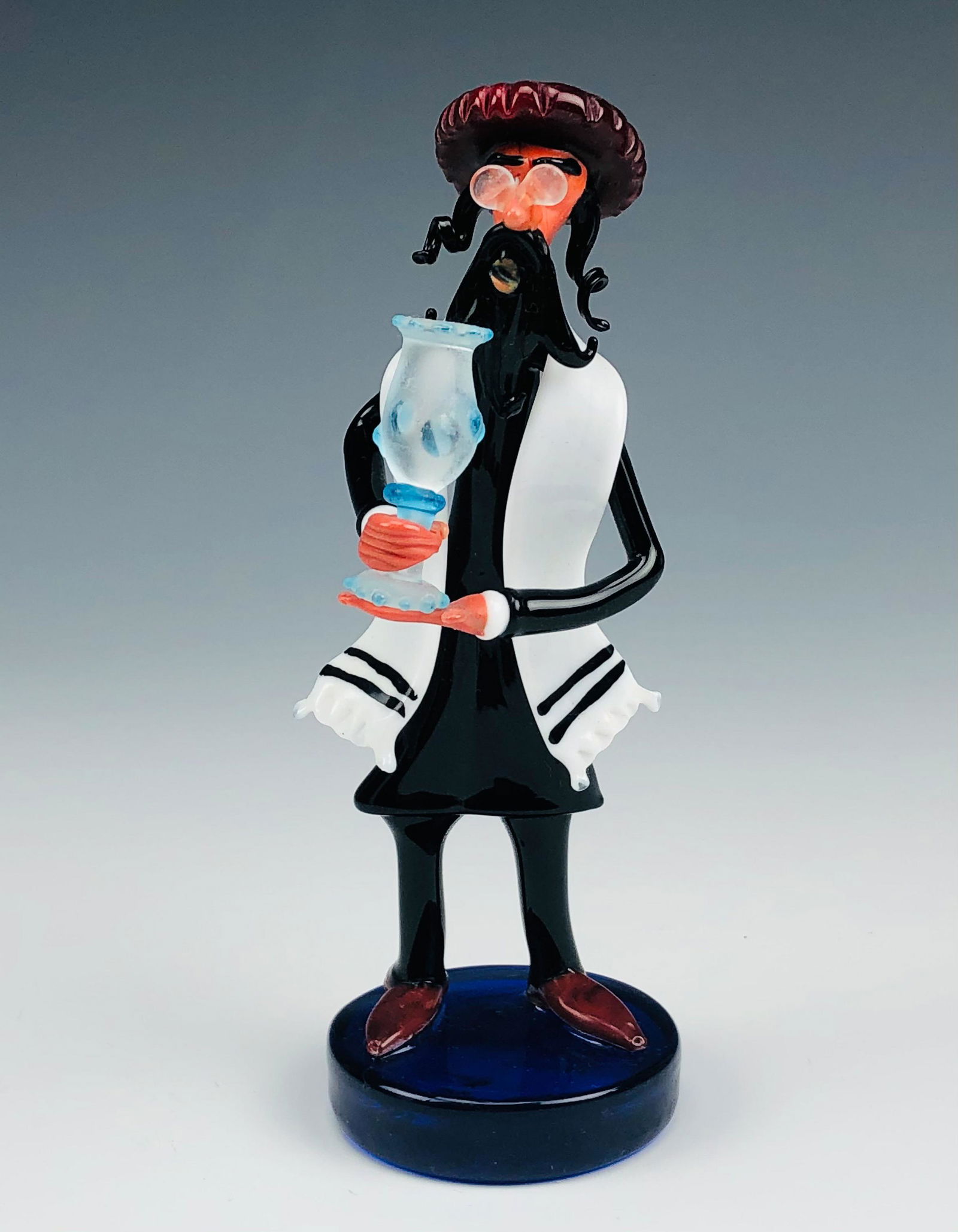 Murano Hasidic Jewish Man Blown Art Glass Figurine: Murano Italy Studio Hand Blown Italian Art Glass Figurine. Modeled with a strongly influenced Judaica themed subject matter. Features a Hasidic Jewish man in standing pose, holding a vase. Mounted ato
