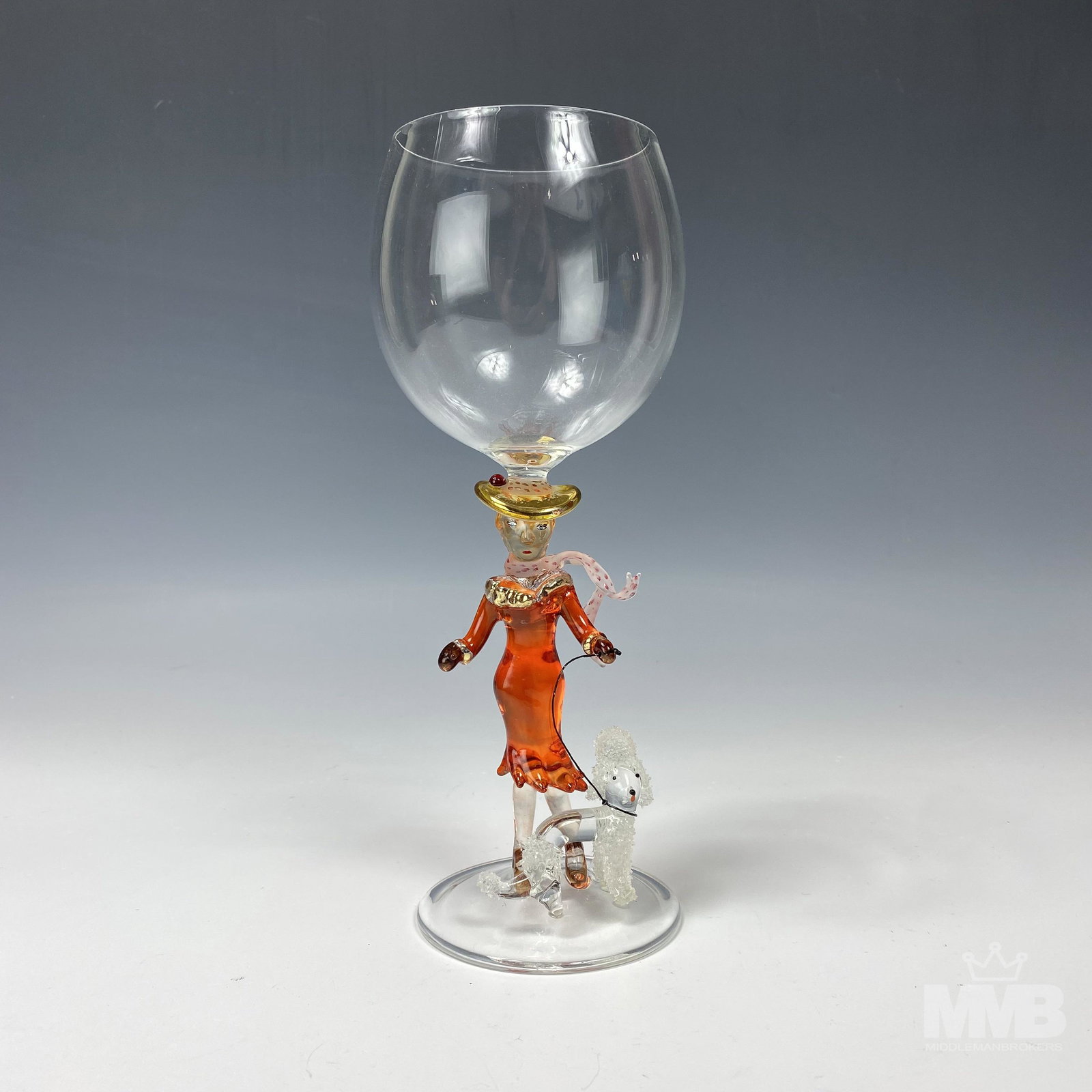 Murano Style Lady w/ Poodle Wine Glass Goblet: Murano style wine goblet features a lady in a red dress and scarf walking her puddle dog. Good condition with minor wear. Measures 9 in. x 3 in x 3 in. Unsigned. MMB Inc. in house USA continental ship