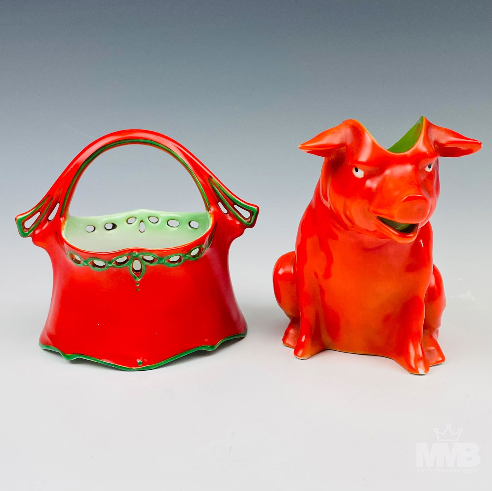 Royal Bayreuth Red Pig Milk Creamer Jug & Basket: Both articles with a red coloration and having a glazed finish. Circa early 20th century. Creamer measures 4 1/4 in. x 4 3/4 in. The basket measures 4 in. x 4 1/2 in. Signed with the blue ink stamp th