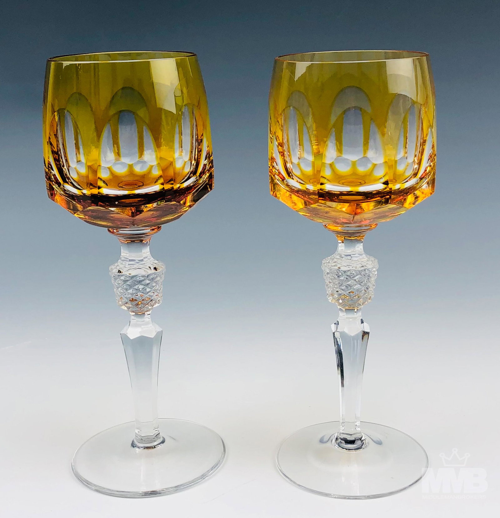 Pair Bohemian Czech Amber Cut Clear Wine Goblets: European origin crystal art glass bar barware wine goblets. The amber colored bodies graced with clear oval cuts around with a geometric pattern below. Multifaceted notched knobs over tapered faceted 