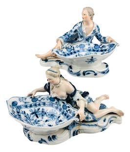 Meissen Blue Onion Figural Sweetmeat Dishes x 2: Late 19th Century hand painted German porcelain figural sweetmeat dishes. Depict a recumbent man and lady, each holding a oval shaped bowl with blue decorations. Measure 7" - 7 1/2" x 11" - 12 1/2". S