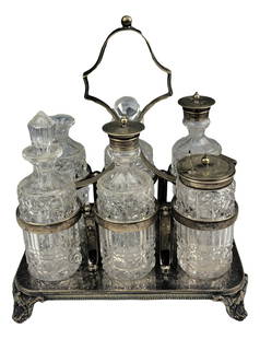 Victorian Silver Plate w/ 6 Glass Bottle Cruet Set: Features 6 clear glass bottles with cut geometric patterns housed in a pierced scroll footed silver plated stand with handle. No monograms. Original weathered patina left intact. Signed EPNS on the un