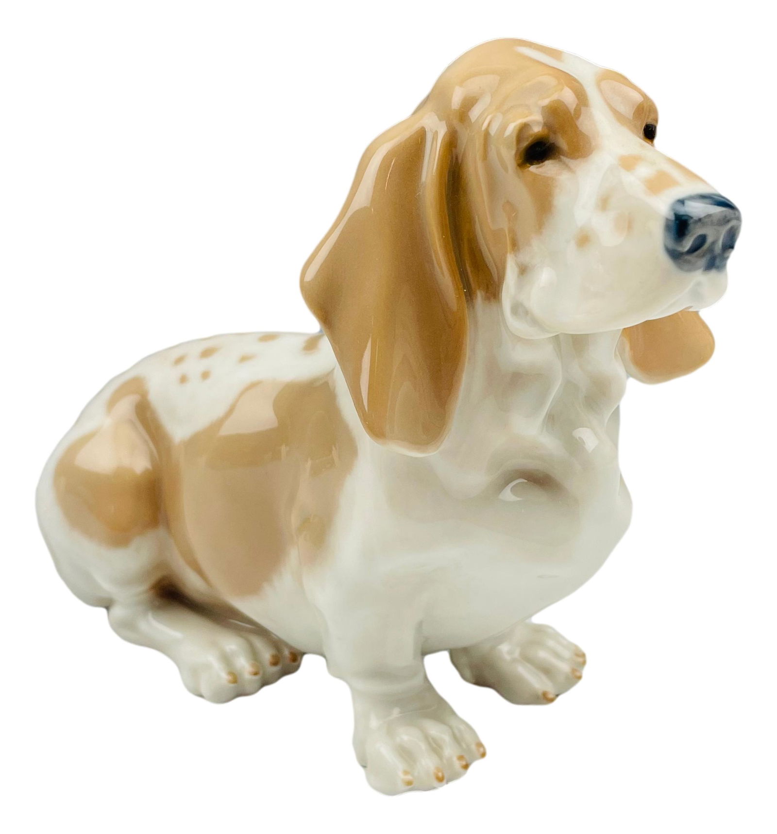 Royal Copenhagen Basset Hound #4616 Dog Figurine: Designed by Jeanne Grut. Model number 4616. Technique : Underglaze. Features this porcelain dog in seated / resting pose. Status : Retired. Measures 4 1/2" x 6". Signed ~ stamped Denmark with the 3 bl