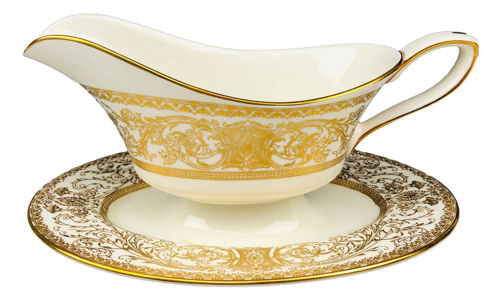 Royal Worcester Embassy Gravy Boat w/ Underplate: 20th century English bone china dinner plates modeled in the "Embassy" pattern by Royal Worcester. Features raised relief ornate gold filigree decorations around the border against a cream ground. Sta