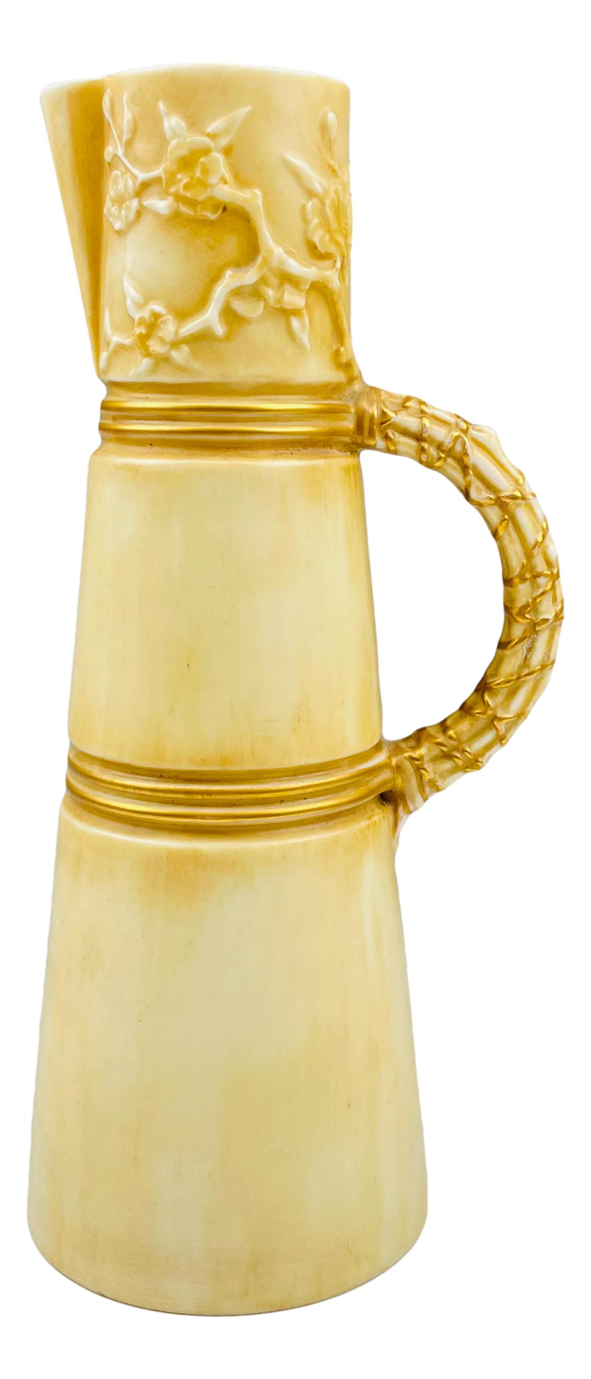Antique Royal Worcester English Porcelain Pitcher: Graced with a cream white colored tapered body with gold tone rings around , the top with a raised relief Art Nouveau inspired floral decoration with pouring spout above, on one side. Ribbed handle wi