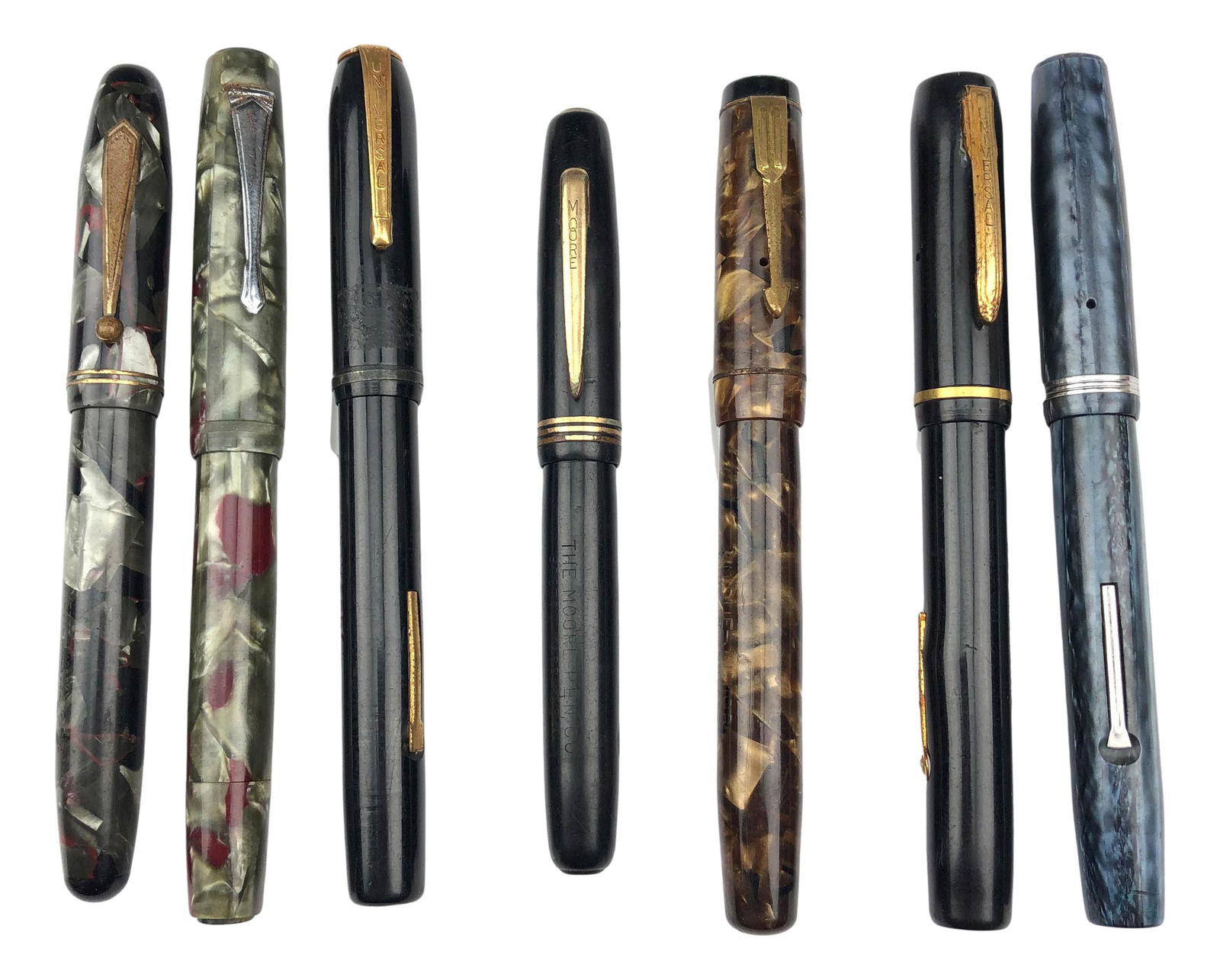 Estate Collection Lot 7 Fountain Desk Writing Pens: Names include ~ 1 x Esterbrook. 1 x Mentmore Unique Junior. 2 x Universal V100. 1 x Parkette. 1 x The Moore pen. One with no apparent markings. Measure from 4 3/8" - 5 3/8". Uncapped 4" - 4 3/4". Post