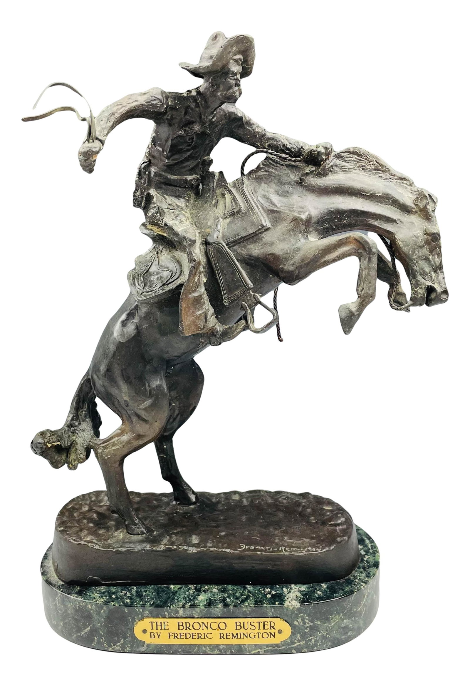 The Bronco Buster Bronze Sculpture After Remington: Subject matter is that of a rugged cowboy attempting to stay aboard a rearing bronco, with a free swing stirrup, a a quirt in one hand, a fistful of mane and reins in the other. Mounted atop and green