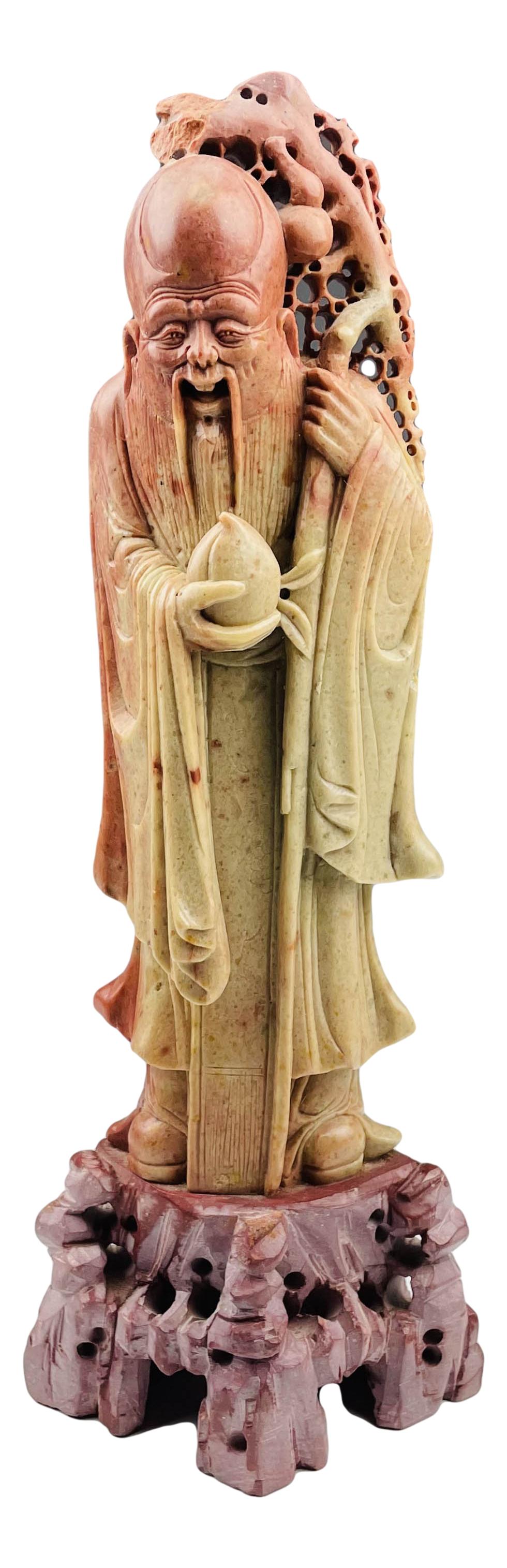 Chinese Export Scholar Man Soapstone Sculpture 16": Hand carved soapstone sculpture depicting a smiley face wise scholar man dressed in a flowing robe, holding a large lucky peach in one hand, the other holding a staff like rod with pierced cut out des