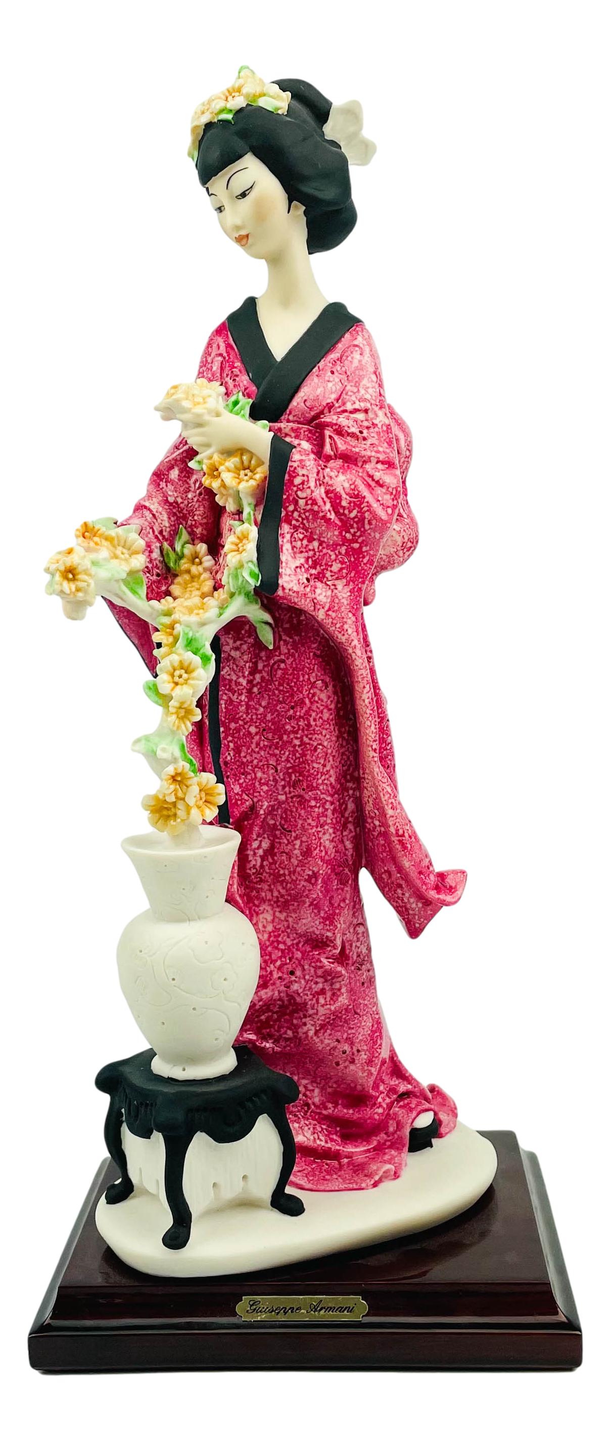 Giuseppe Armani Oriental Lady Flower Pot Figurine: Giuseppe Armani ( Italian, 1935 - 2006 ). Celebrated and internationally respected artist / designer and sculptor. Depicts a Geisha woman holding and looking at flowers in a pot. Mounted atop a rectan