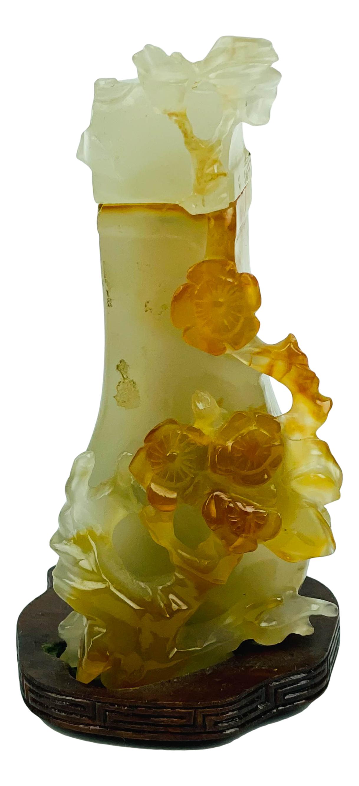 Chinese Carved Carnelian Stone Floral Lidded Vase: Hand carved Semi Precious gemstone small floral vase with lid. Affixed to a dark colored irregular shaped wooden base. NO apparent markings. Dimensions: 4.25 X 2.25 X 2.25 in. Condition: Good to
