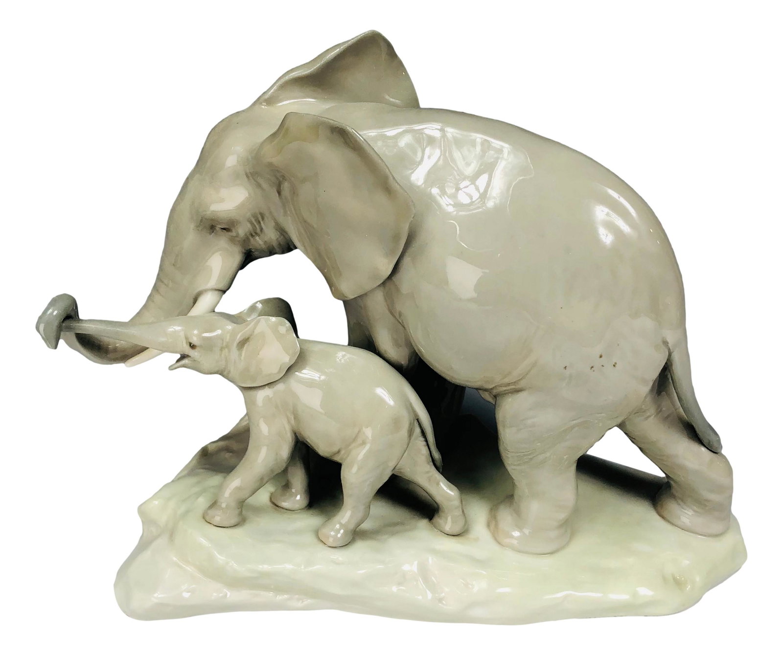Lladro Elephant Mother & Baby Porcelain Figurine: Lladro Spain mother elephant and baby porcelain figurine statue. Features mother elephant holding trunks with baby calf in walking position. Marked Lladro Spain on bottom. Dimensions: 7.25 X 9 X 4 in.