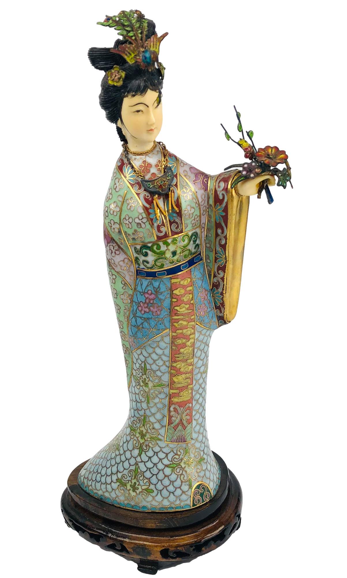 Chinese Cloisonne Enamel Empress Figurine 12.5": handcrafted article of Chinese cultural art depicting a stately Chinese royalty style woman in standing pose holding a floral arrangement in one hand and a decorative kimono. Affixed to a dark colored