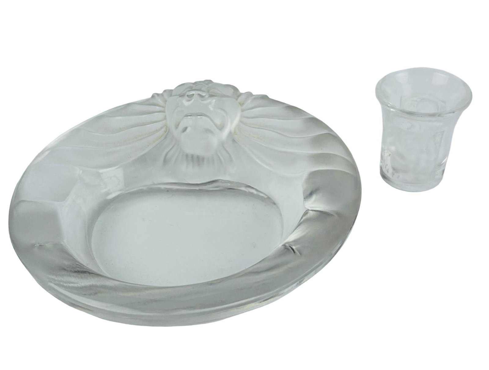 Lalique Tete De Lion Ashtray Les Enfant Shot Glass: 20th century Lalique France French frosted crystal art glass bowl and jigger cup. The round ashtray bowl showcases a lion's head with its gorgeous flowing mane. The "Les Enfants" shot glass features n