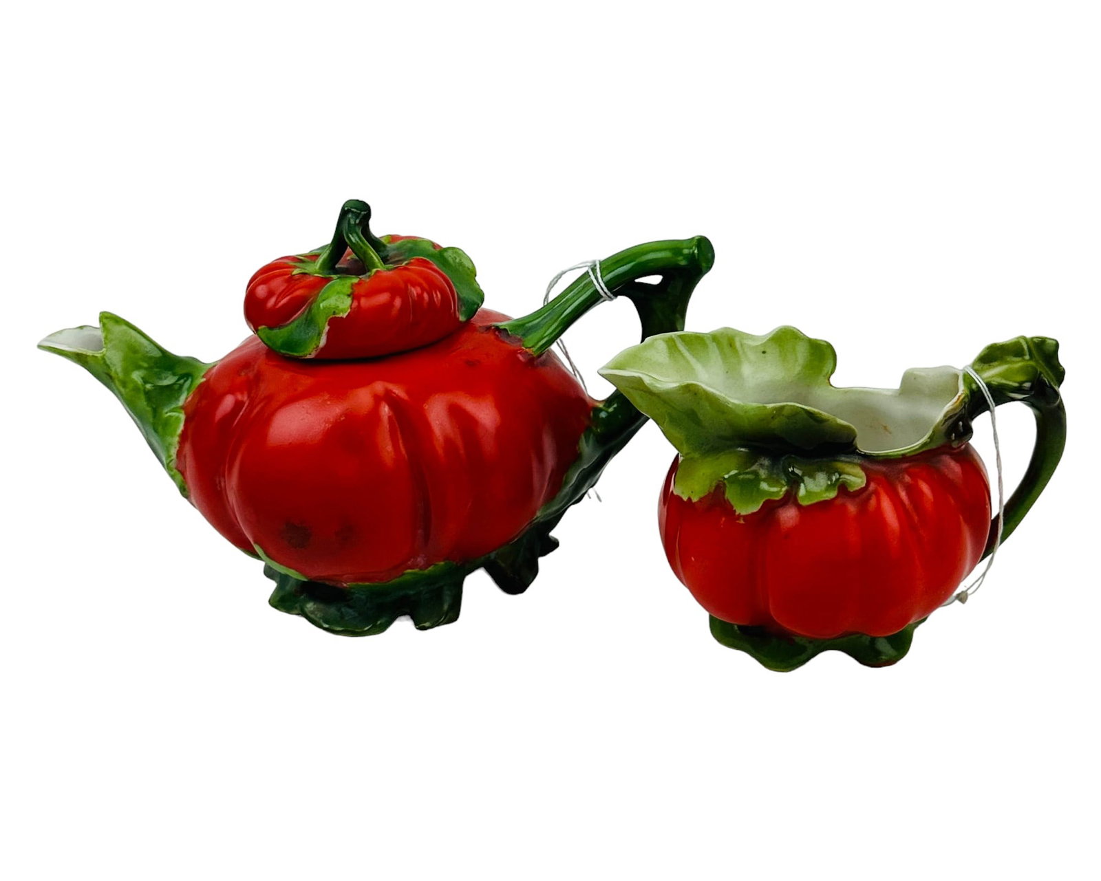 Royal Bayreuth Porcelain Tomato Teapot & Creamer: A two-piece set of German porcelain in the tomato pattern. The set includes (1) teapot with lid and (1) creamer mini pitcher with handle, both featuring bold-colored hand-painted details. The creamer 