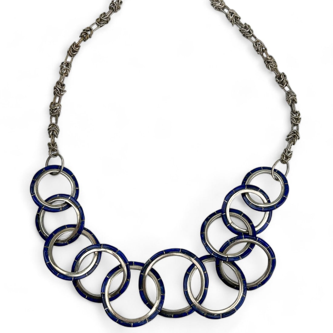 Modernist Sterling Silver Cobalt Enamel Necklace: Features a modernist design consisting of interlocking rings with vibrant cobalt enamel and masterfully paired with a sterling silver 925 Byzantine-style chain. Measures approximately 34". No apparent