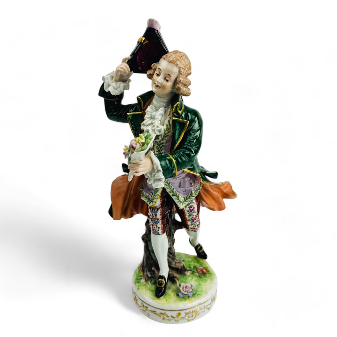 Antique German Porcelain Victorian Man Figurine: Early 20th century hand painted German porcelain figurine. Features a finely groomed Victorian gentleman, dressed in a vibrant green coat with gold accents, wearing a powdered wig. holding a bouquet o
