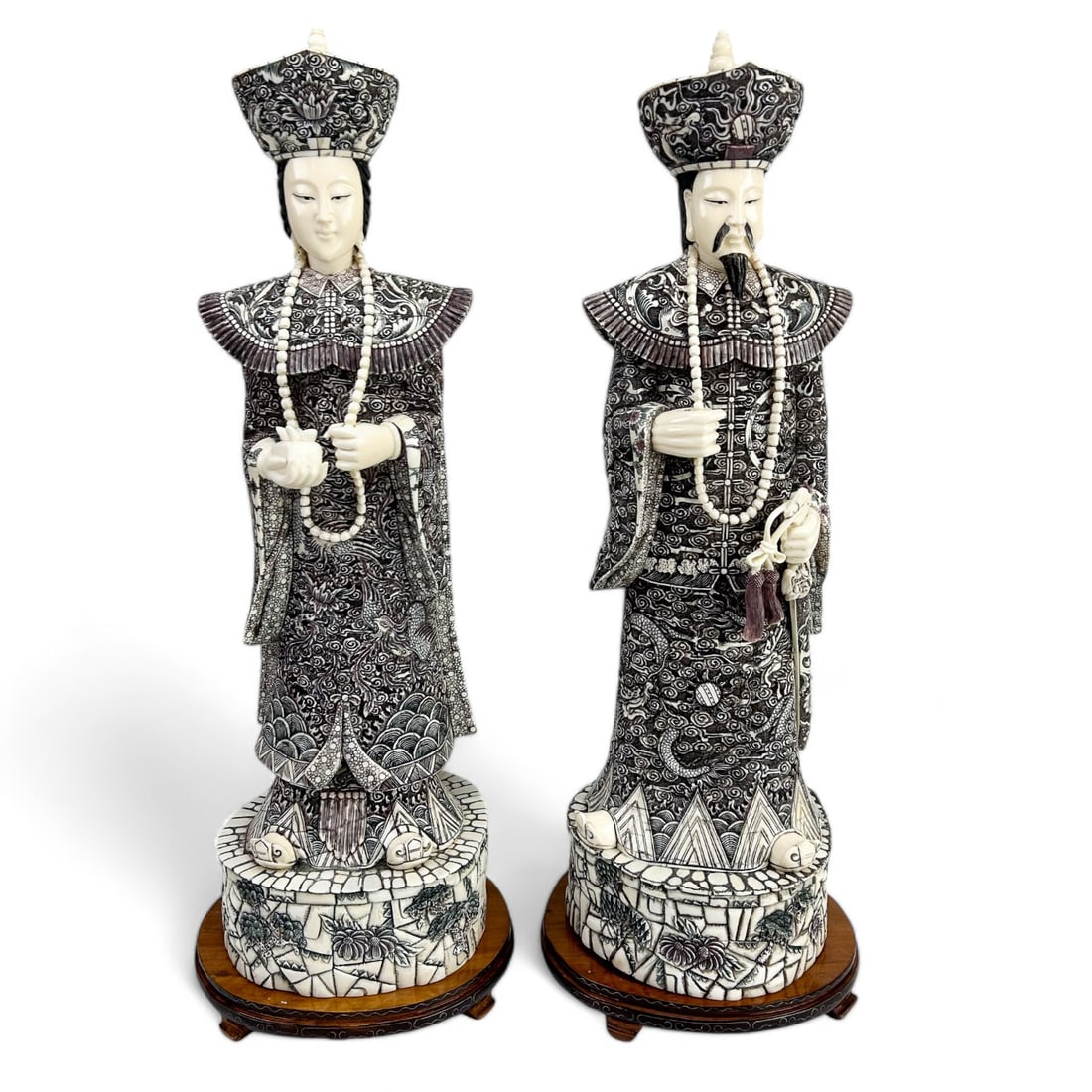 Chinese Emperor Empress Carved Figures w Wood Base: A finely detailed pair of hand-carved Chinese emperor and empress figures, possibly crafted from bovine or ox bone. Both the male and the female sculpture showcase intricate carvings depicting traditi