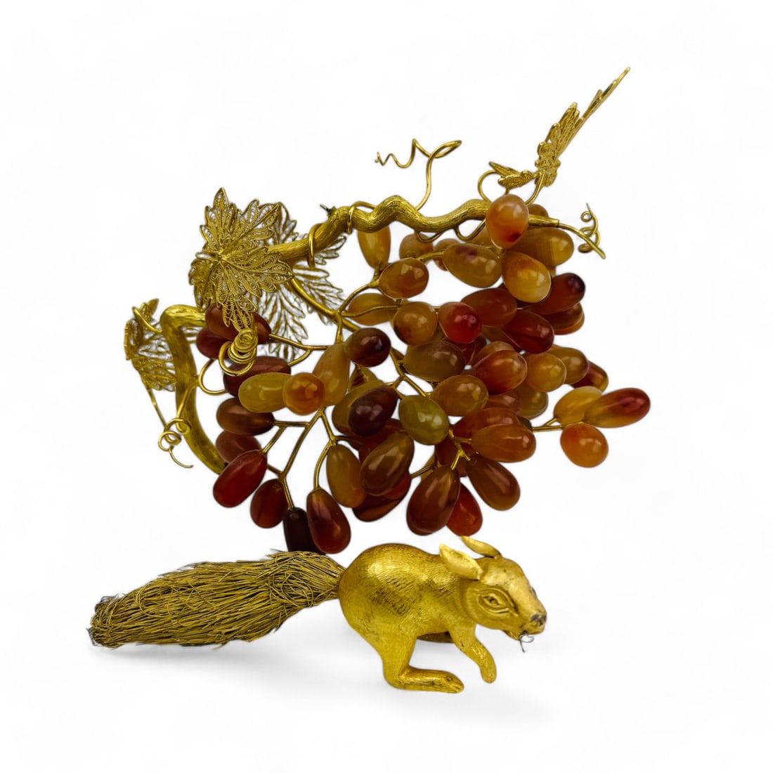 Chinese Gilt Silver Squirrel with Carnelian Grapes: An exquisite sculpture that features a finely crafted gilt silver squirrel perched top a cluster of hardstone grapes. The sculpture showcases intricate gold gilt filigree detailing in the leaves. The 