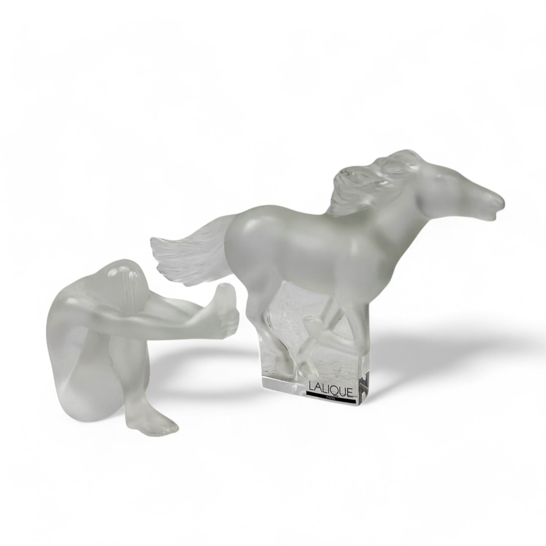 Lalique France Crystal Horse & Nude Lady Figurine: An estate lot of a total of two (2) Lalique French frosted crystal satin finish sculptures. Includes ~ One (1) "Kazak" galloping mustang horse, showcasing a dynamic equestrian form on a clear crystal 