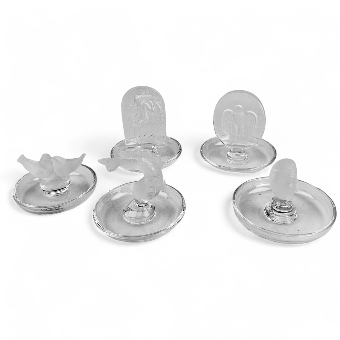 Lalique France Crystal Ring Pin Trinket Dish LOT: An estate grouping of a total of five (5) Lalique France frosted and clear crystal ring holders, each featuring an iconic design. Patterns include ~ One(1) Naiade (Nude Dancing Nymph). One (1) Colombe