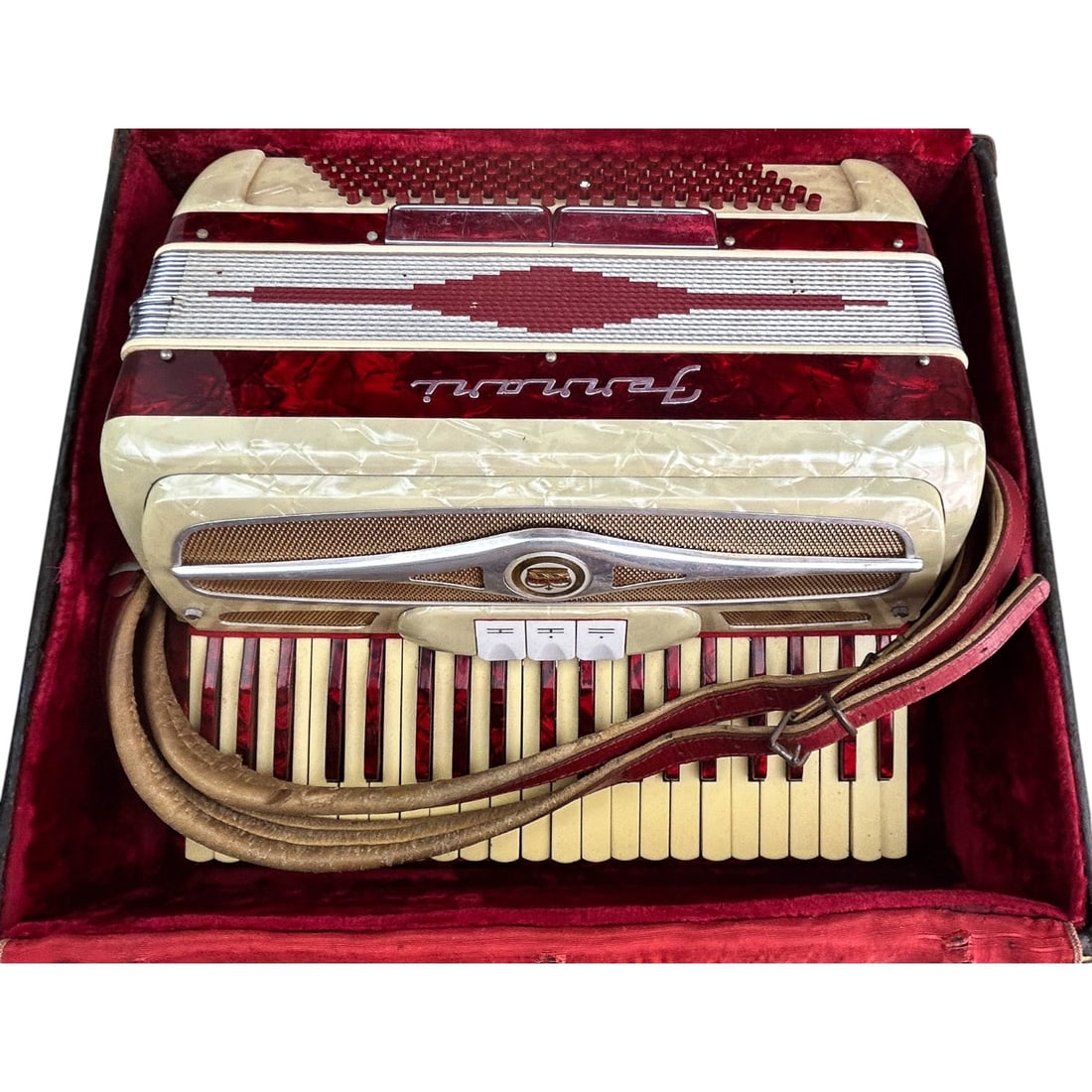 Ferrari Italy Red Cream Piano Accordion w/ Case: Vintage Ferrari accordion featuring a striking red and cream pearloid finish with intricate decorative patterns. The body highlights a vibrant red marbled veneer, accented with elegant white keys and