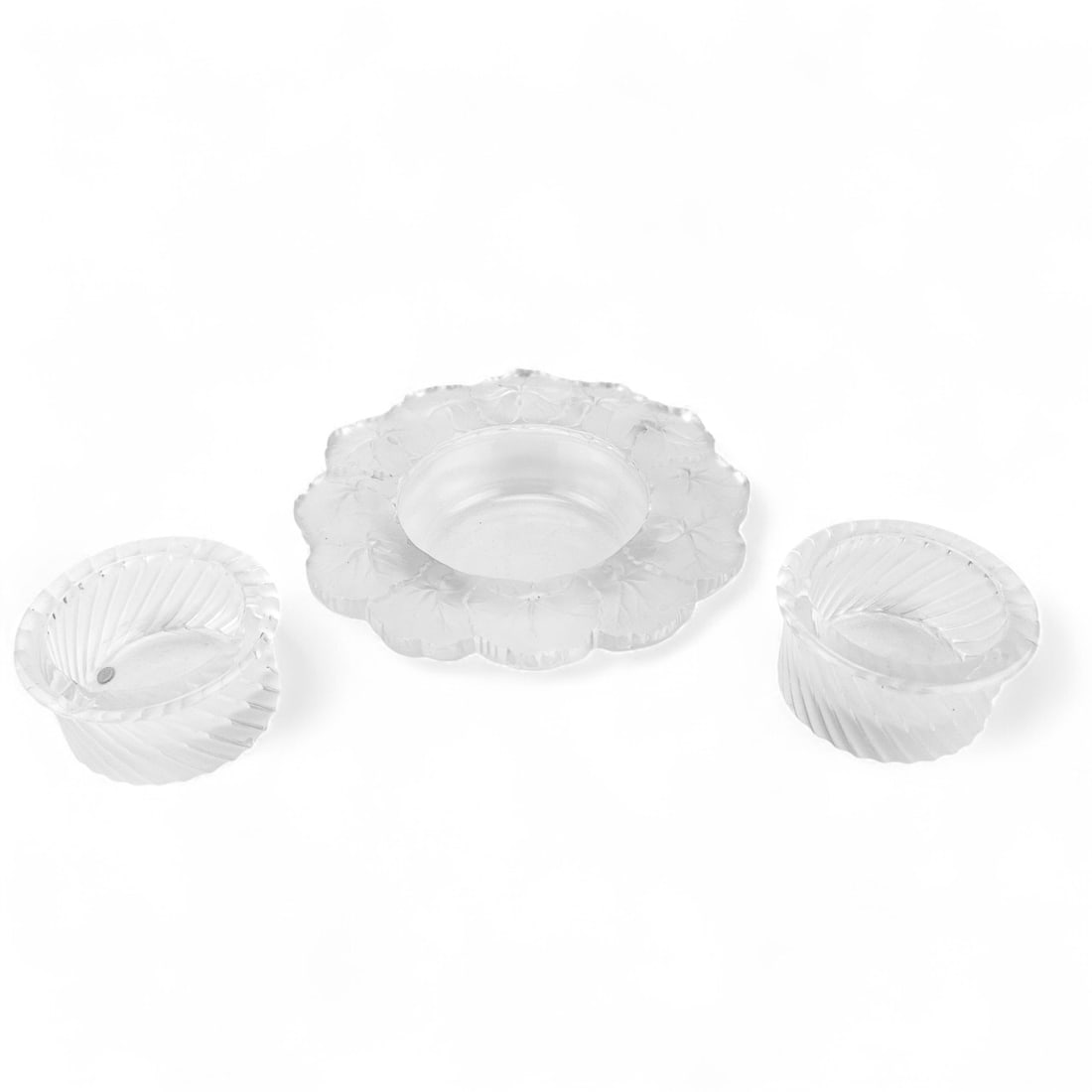 Lalique Smyrne Ashtrays & Honfleur Nut Bowl 3p LOT: 20th century Lalique French frosted and clear crystal art glass decorative objects. Includes ~ two (2) Smyrne pattern cigarette ashtray dish bowls having a smooth rim with a swirl segmented pattern ar