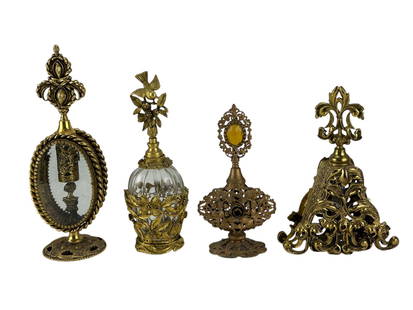French Rococo Gilt Brass Dresser Perfume Bottle 4p: French Rococo style lot of four gilt brass ormolu scent bottles featuring ornate scrollwork, floral motifs and figural finials. Includes an amber jewel topped bottle, a pyramid form with fleur de lis