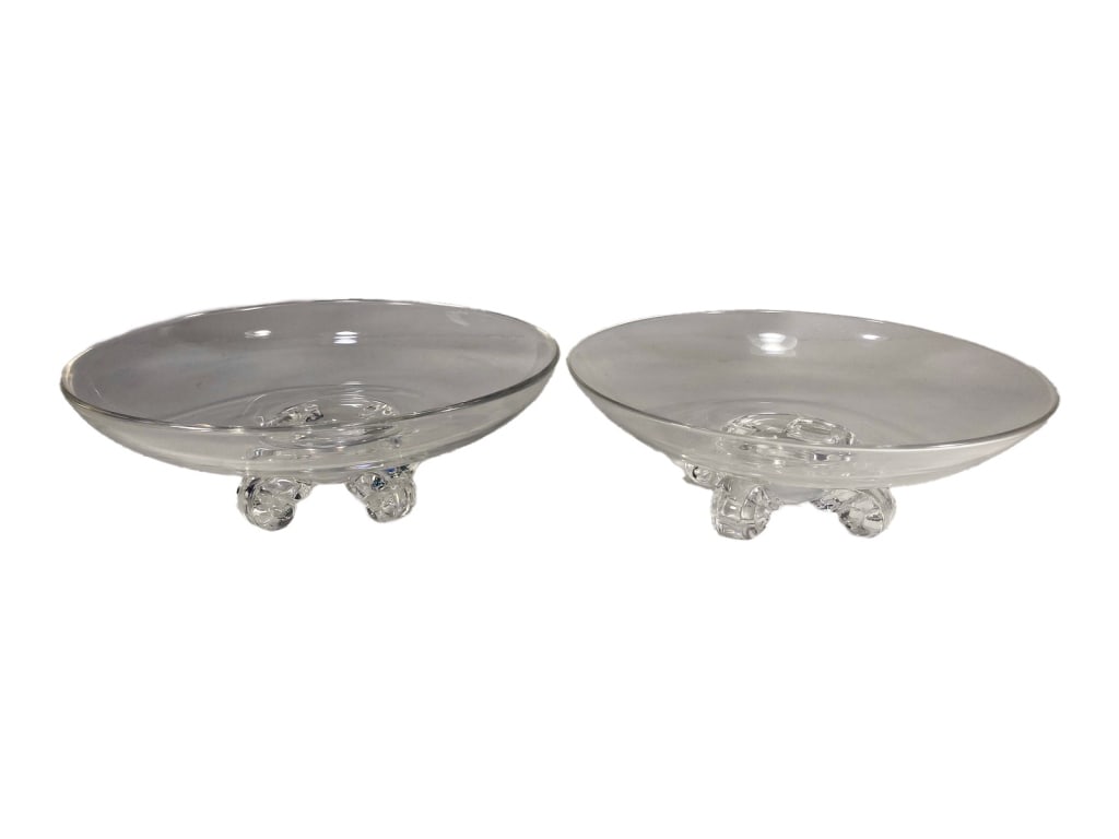 Steuben Crystal Scroll-Footed Low Bowls 2pc LOT: Steuben, a pair of shallow round crystal low bowls with wide open rims, each supported on three curled scrolled feet. Signed 'Steuben' in script to their underside. The largest measures approximately