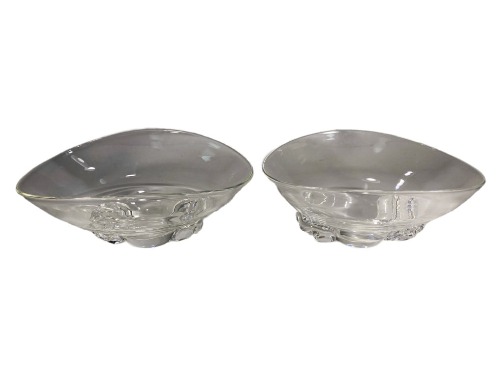 Steuben Pair of Basket-Shaped Clear Crystal Bowls: Two Steuben clear crystal bowls with freeform asymmetrical rims, each resting on a thick applied base. Both signed 'Steuben' in script to their underside. The largest measures approximately 4.75 inche