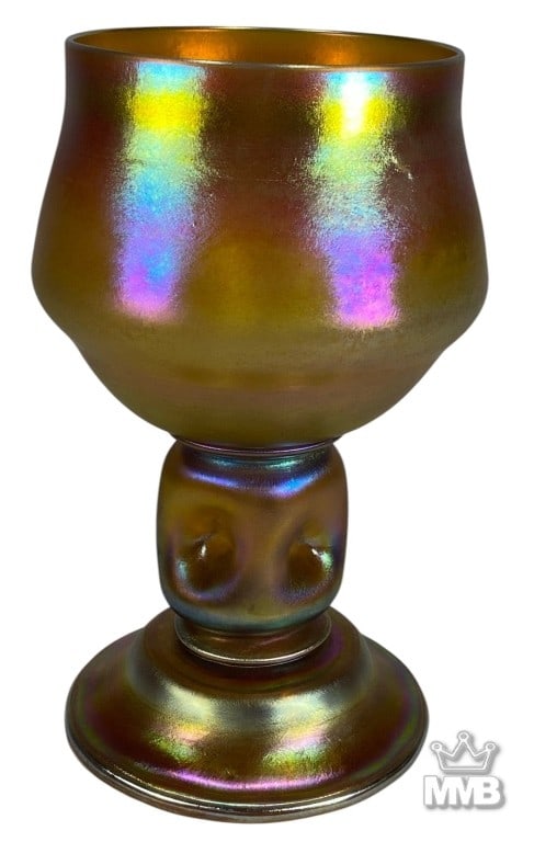 Favrile Iridescent Art Glass Goblet after Tiffany: Tall iridescent art glass goblet after Tiffany, with a flared amber bowl, rainbow iridescence, knop stem, circular foot, and polished pontil with faint initials. The underside shows a polished pontil