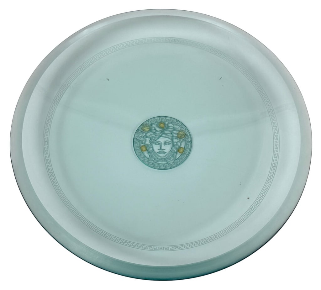 Rosenthal Versace Medusa Center Bowl & Plaque: This lot includes a large Versace art glass center bowl featuring a reticulated Greek key border and centralized Medusa head motif. Accompanied by retail Versace by Rosenthal signage plaque. The bowl