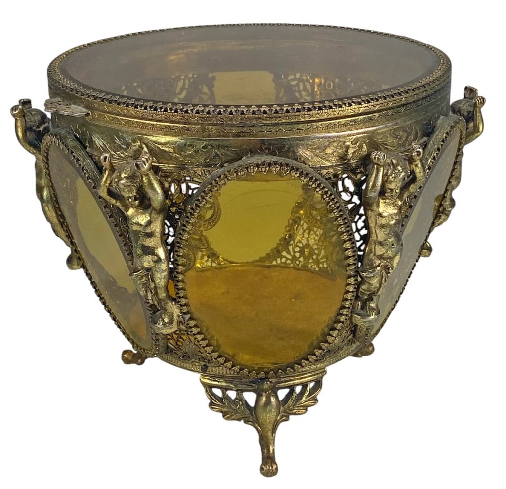 Cherubs Gilt Metal & Beveled Glass Casket Box: Gilt metal casket box with amber beveled glass panels, supported by cherub figures and floral mounts on four legs. Dimensions: 6 X 7.25 X 7.25 in. Condition: Good overall condition having normal su