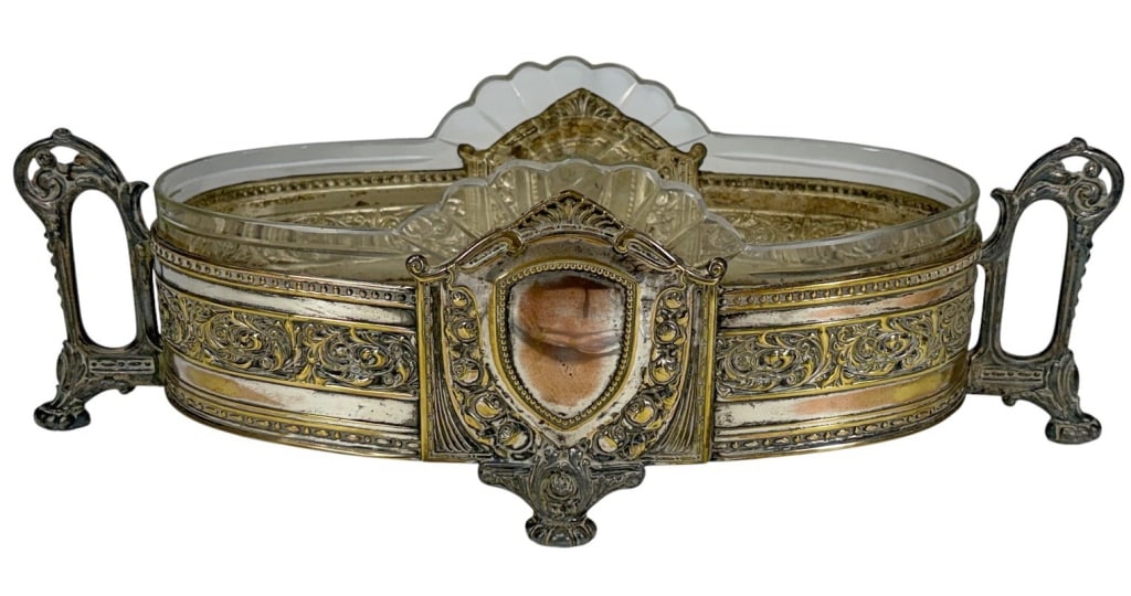 German Art Deco Silverplated & Glass Jardiniere: German Art Deco silverplated oval jardiniere with pierced handles, floral repousse bands, gilt accents, and removable glass liner. Marked 'Alemania.' Dimensions: 4.75 X 14.5 X 5.5 in. Condition: Go
