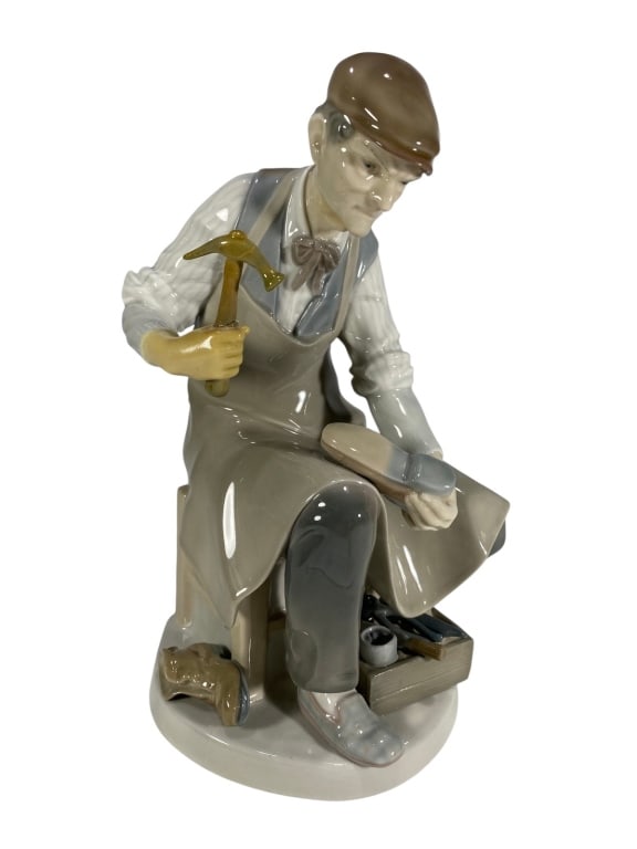 Lladro Cobbler Spanish Porcelain Figurine #4853: Lladro porcelain figurine titled 'Cobbler' depicting a shoemaker seated on a stool with apron and cap, holding a hammer and shoe. A toolbox with tools and shoes rests at his feet. Model number 4853. T