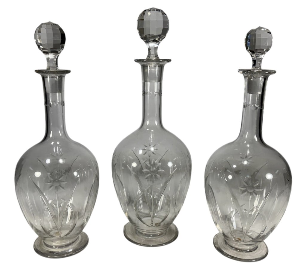 Baccarat French Floral Motif Glass Decanters 3pcs: Baccarat French crystal decanters with engraved floral motifs, faceted stoppers, and bases retaining Baccarat France labels. The largest measures approximately 12.75 inches tall by 4.25 inches wide by